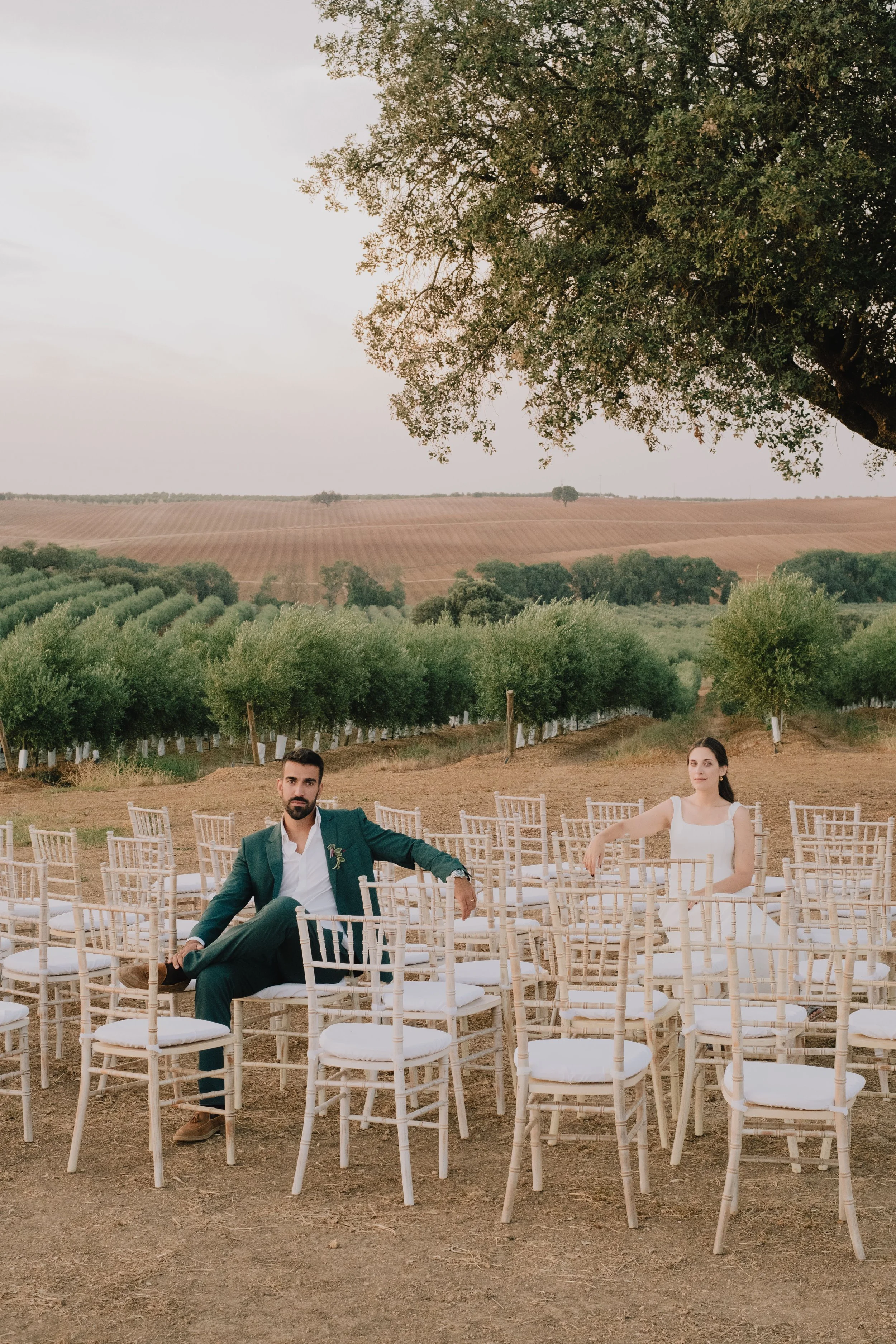 Bride and groom sitting among ceremony chairs in an outdoor wedding setting in Portugal
