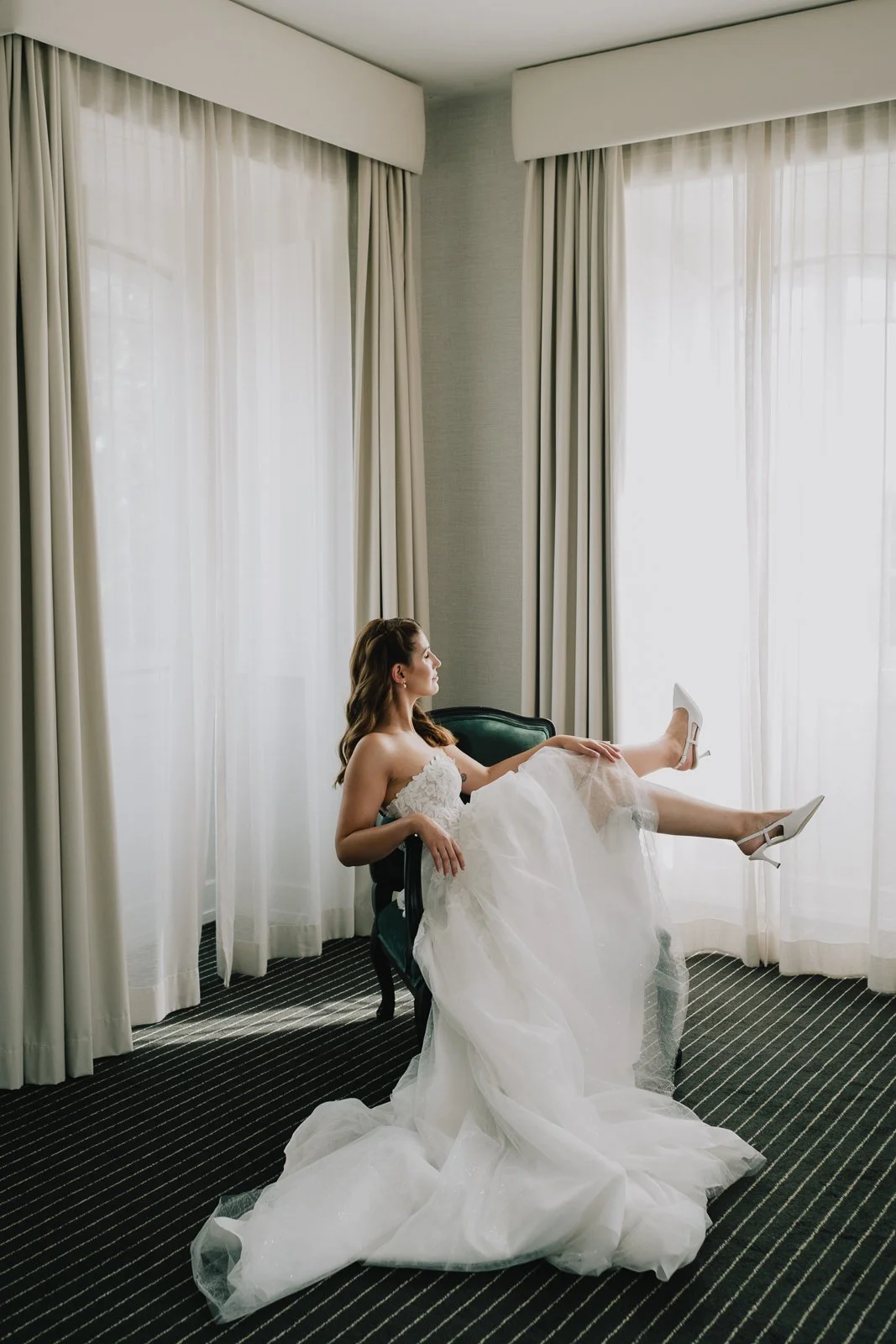 Bride adjusting her dress during wedding preparation in Portugal in a soft and elegant setting