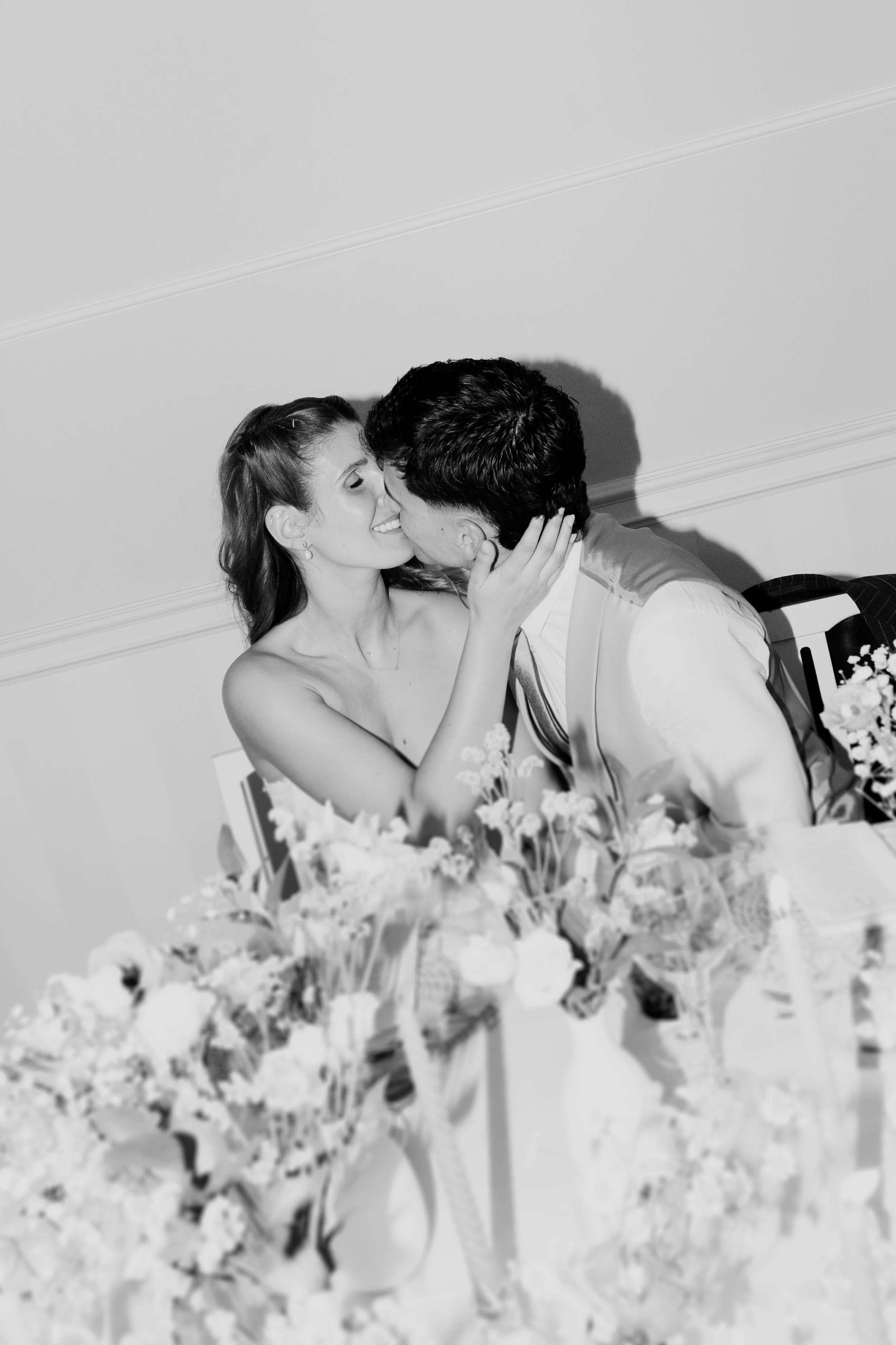 Bride and groom sharing a romantic kiss at a decorated table during a wedding in Portugal