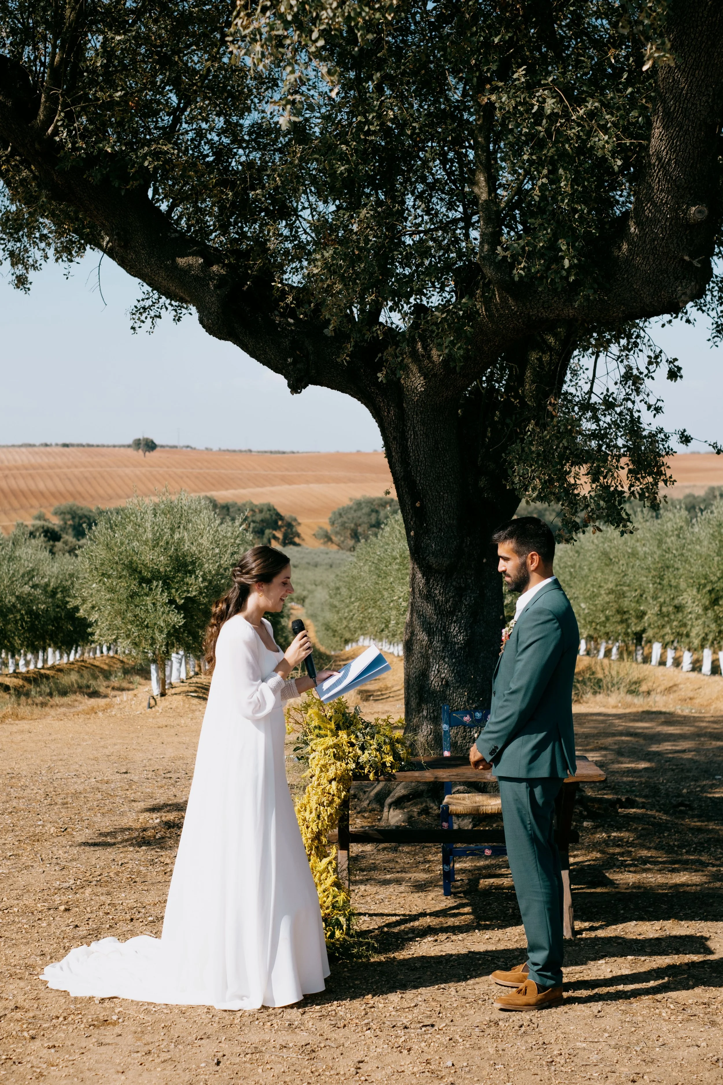 Outdoor wedding ceremony in Portugal with bride and groom under a large tree in a natural setting