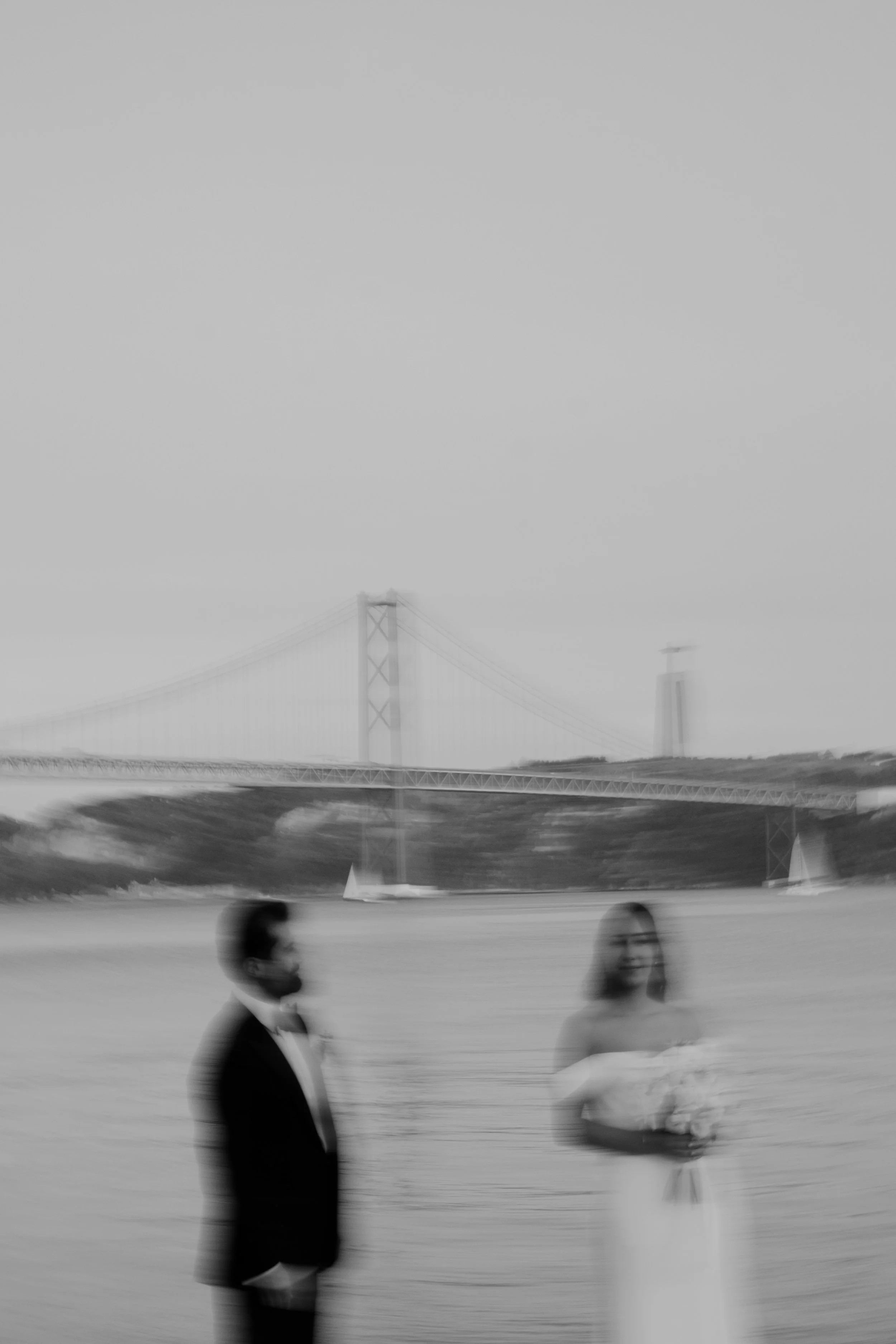 Wedding couple in Lisbon with a bridge in the background captured in a soft and artistic blur
