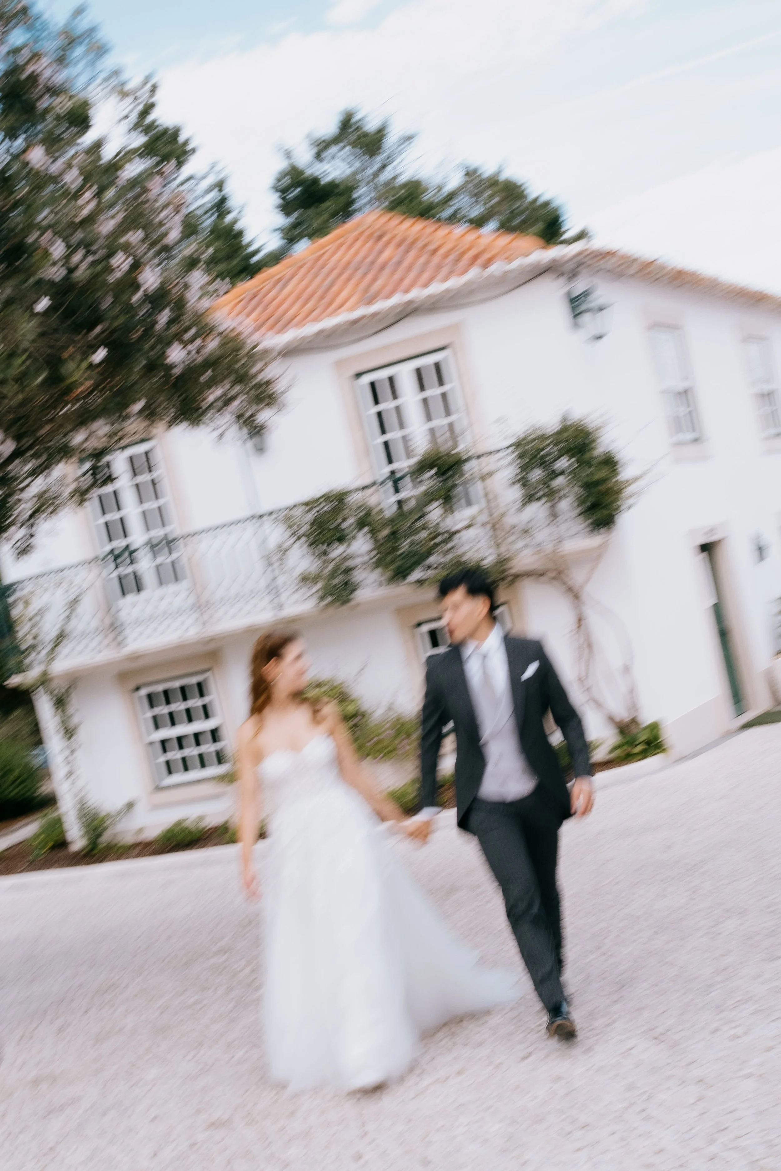 Bride and groom walking together in front of a traditional villa during a wedding in Portugal