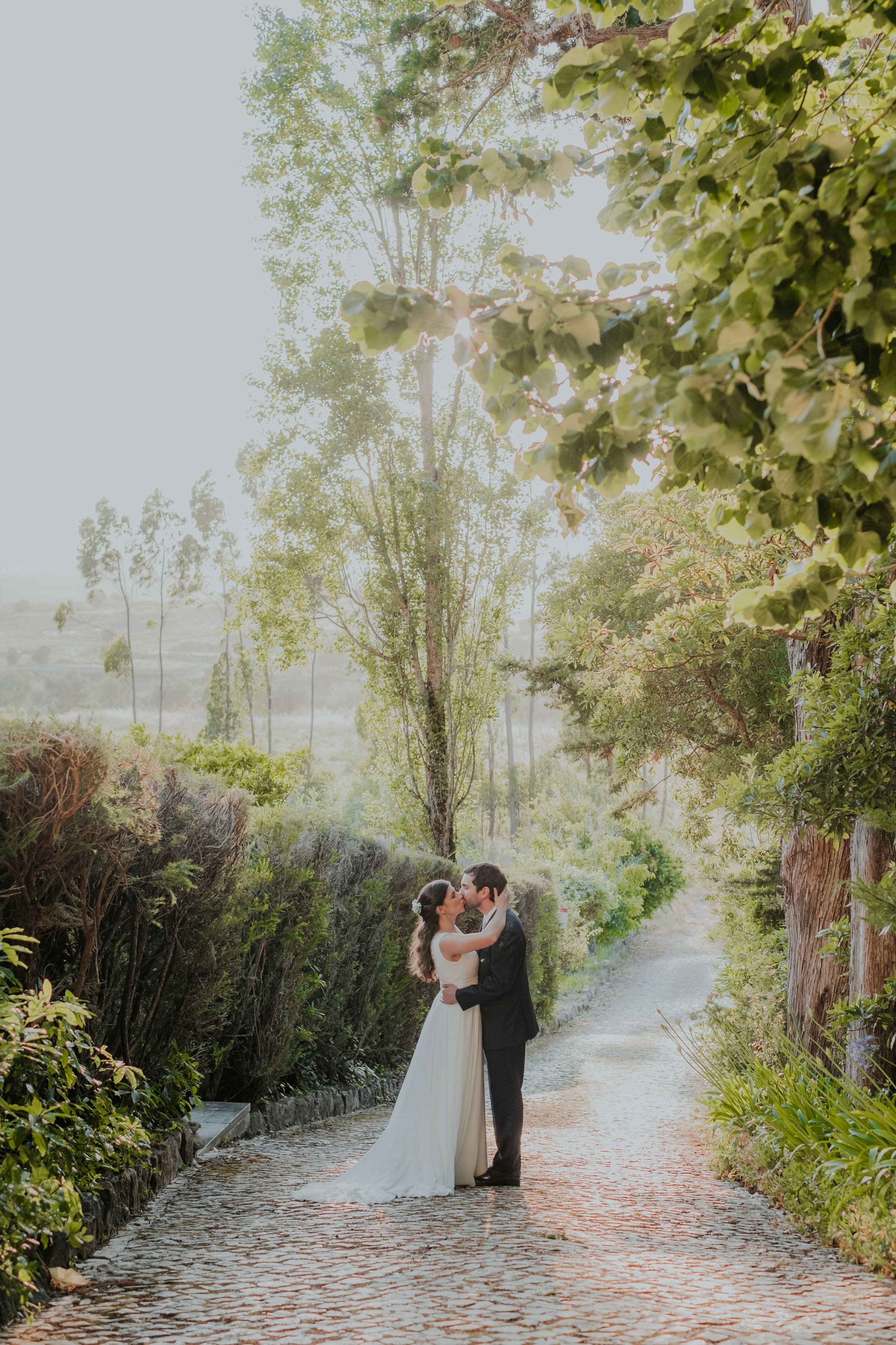 Bride and groom embracing on a natural path surrounded by greenery during a wedding in Portugal