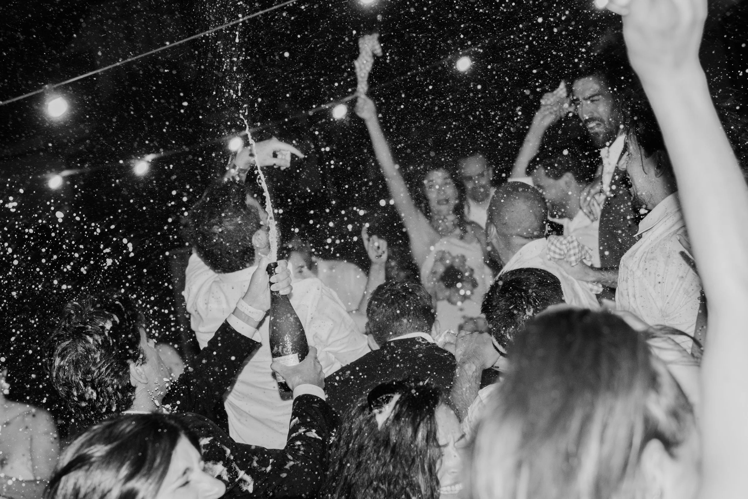 Guests celebrating at a wedding party at night with champagne and joyful atmosphere