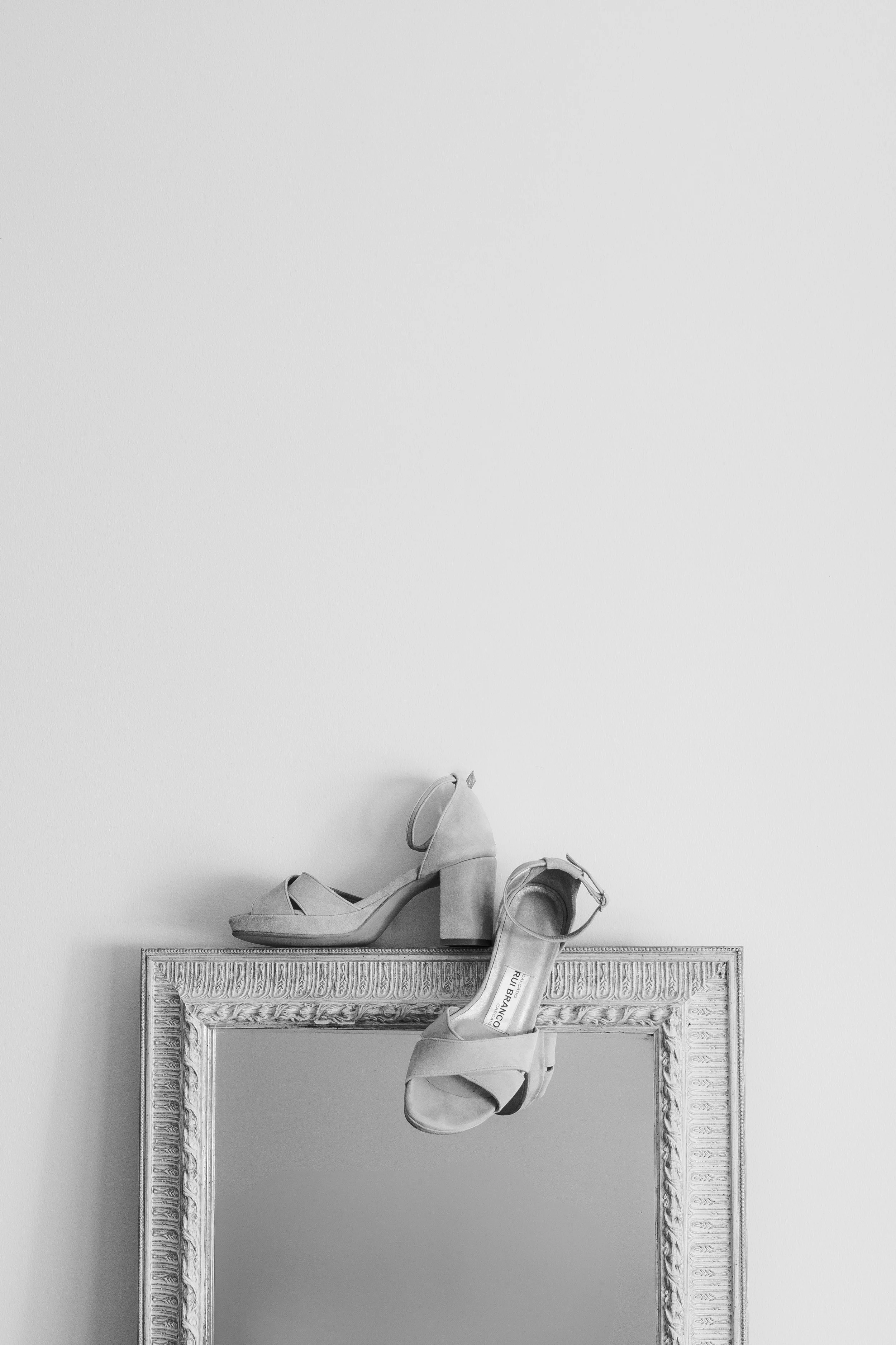 Minimalist bridal shoes placed on a frame in an artistic and editorial wedding detail composition
