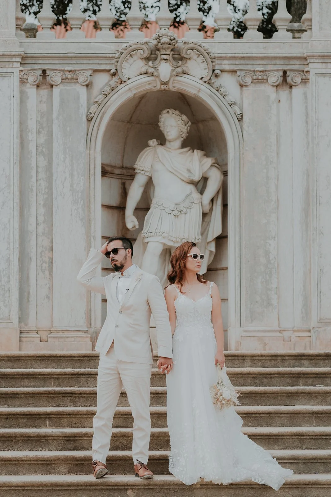 Bride and groom standing on elegant stairs with classical architecture during a wedding in Portugal