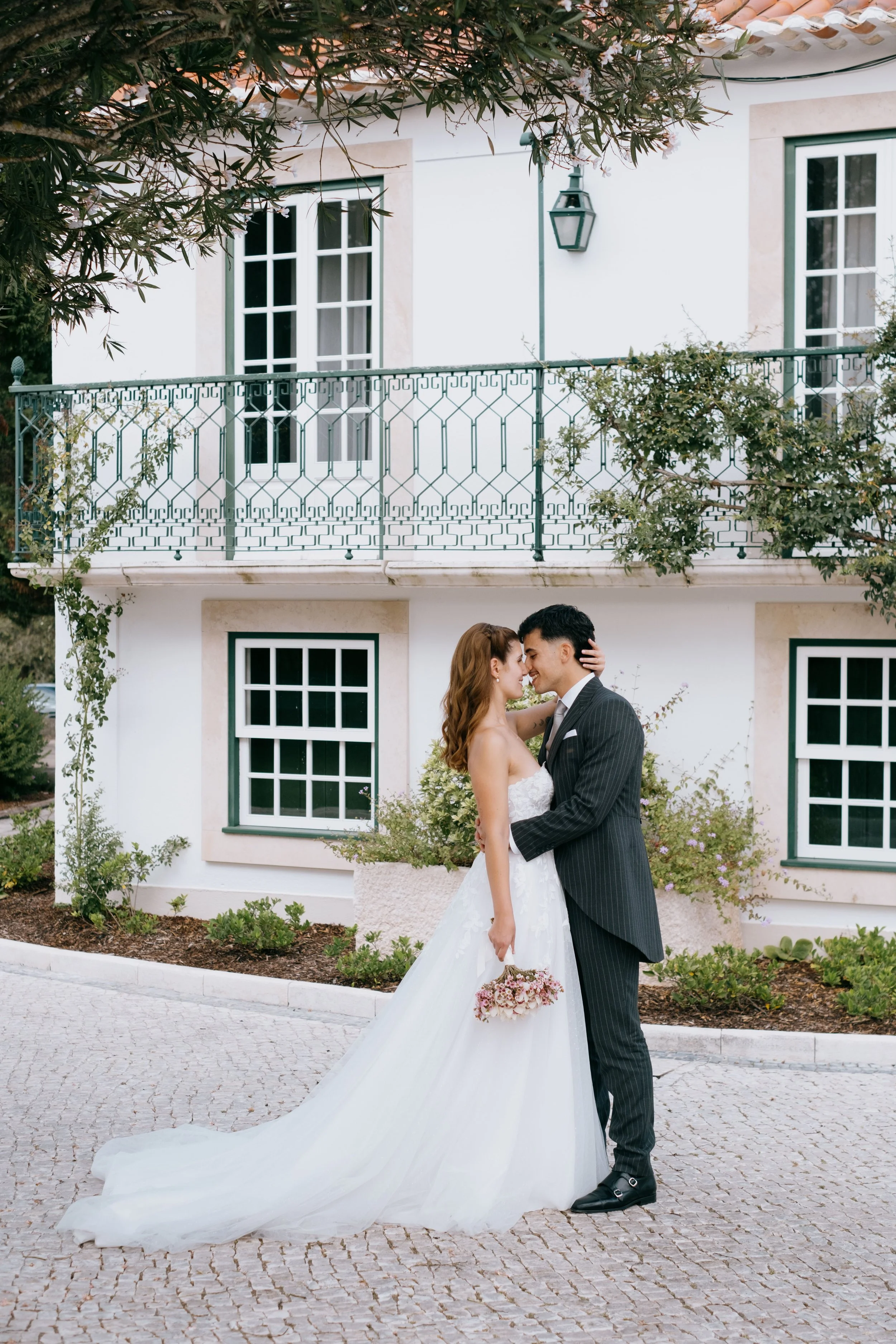 Bride and groom embracing in front of a traditional villa during a wedding in Portugal