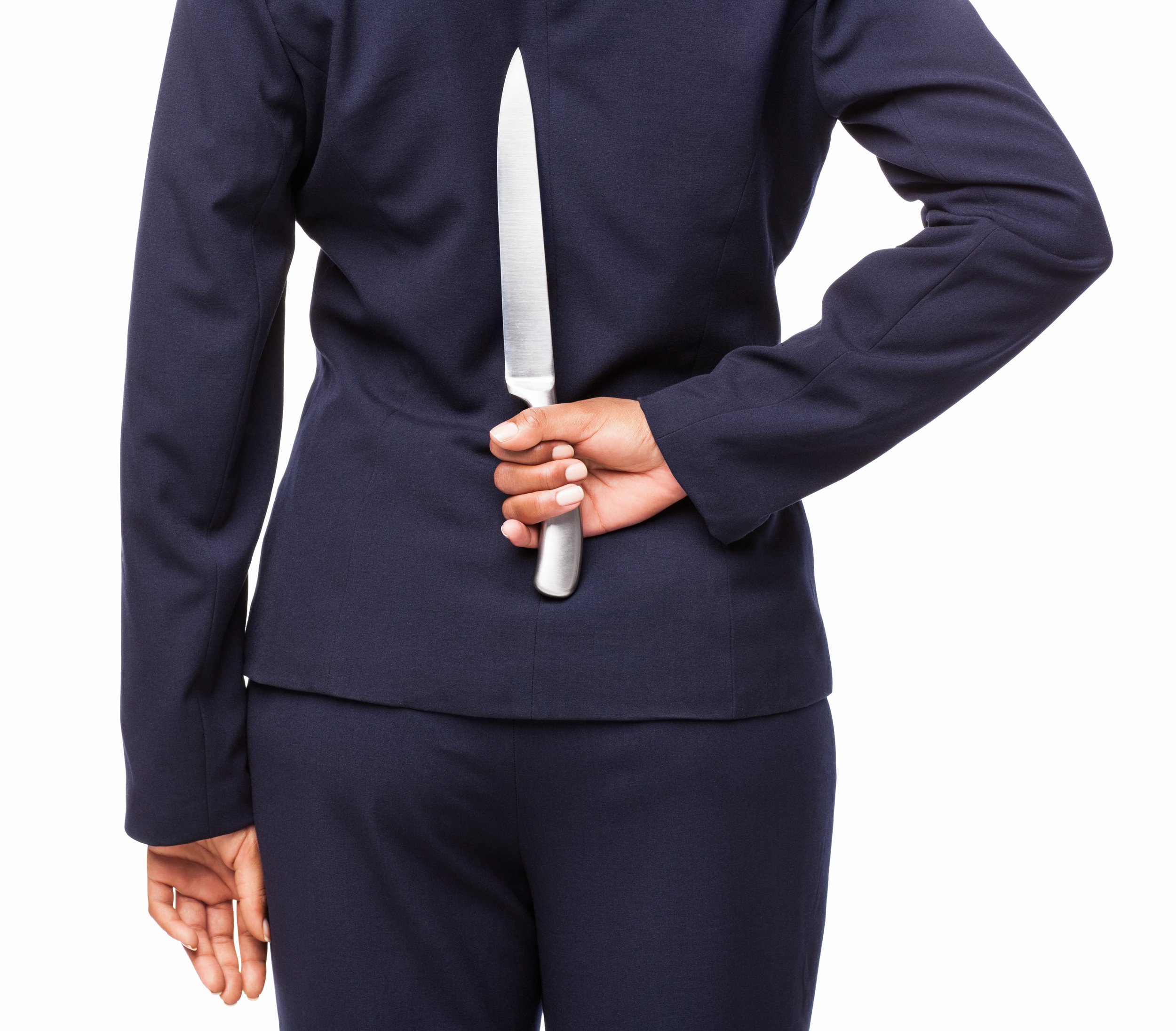 Person in a dark suit holding a large kitchen knife behind their back.