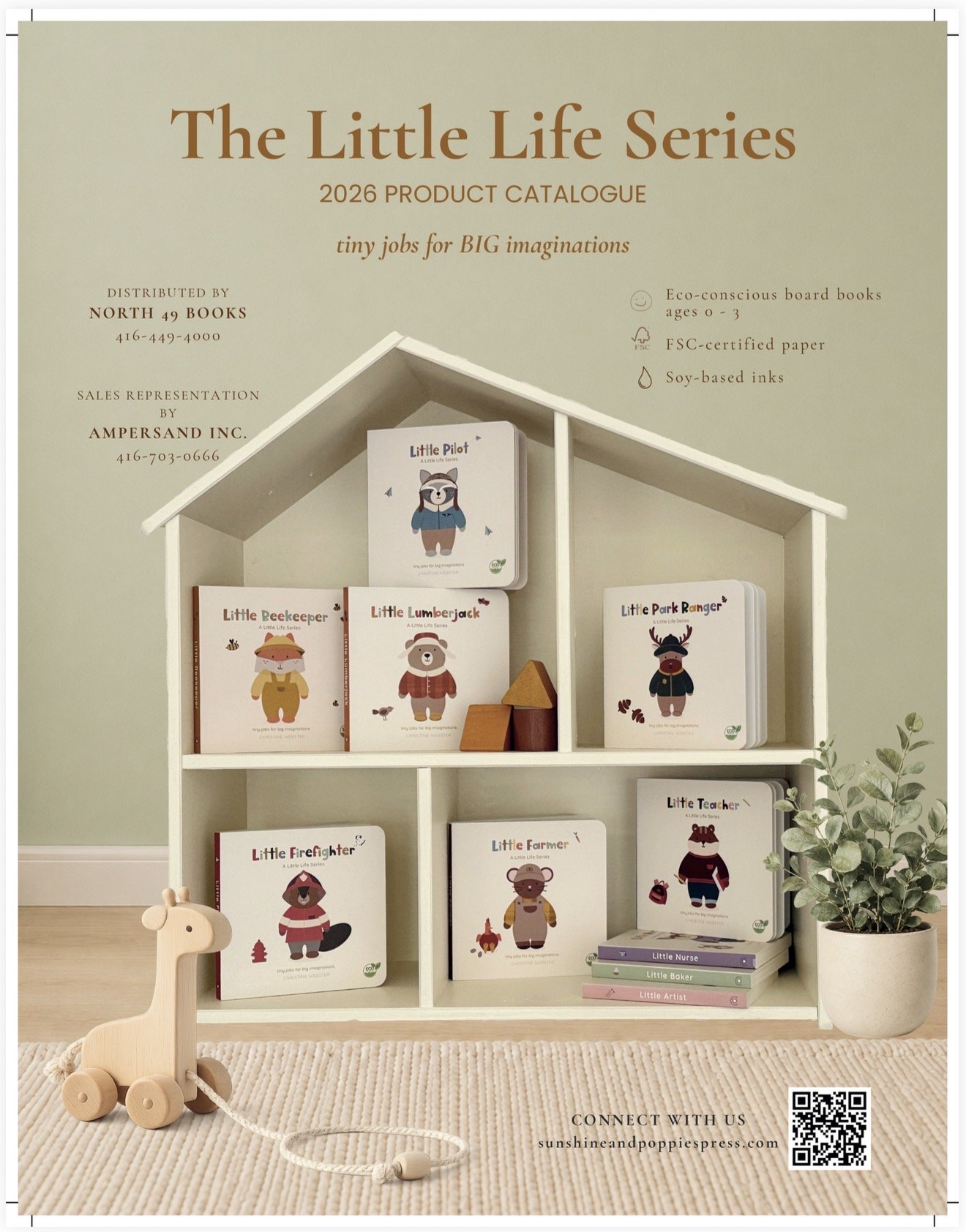 Display of children's books arranged on a white bookshelf shaped like a small house, with a wooden pull toy giraffe in the foreground and a potted plant on the right side. The books feature animal characters and are part of 'The Little Life Series.'