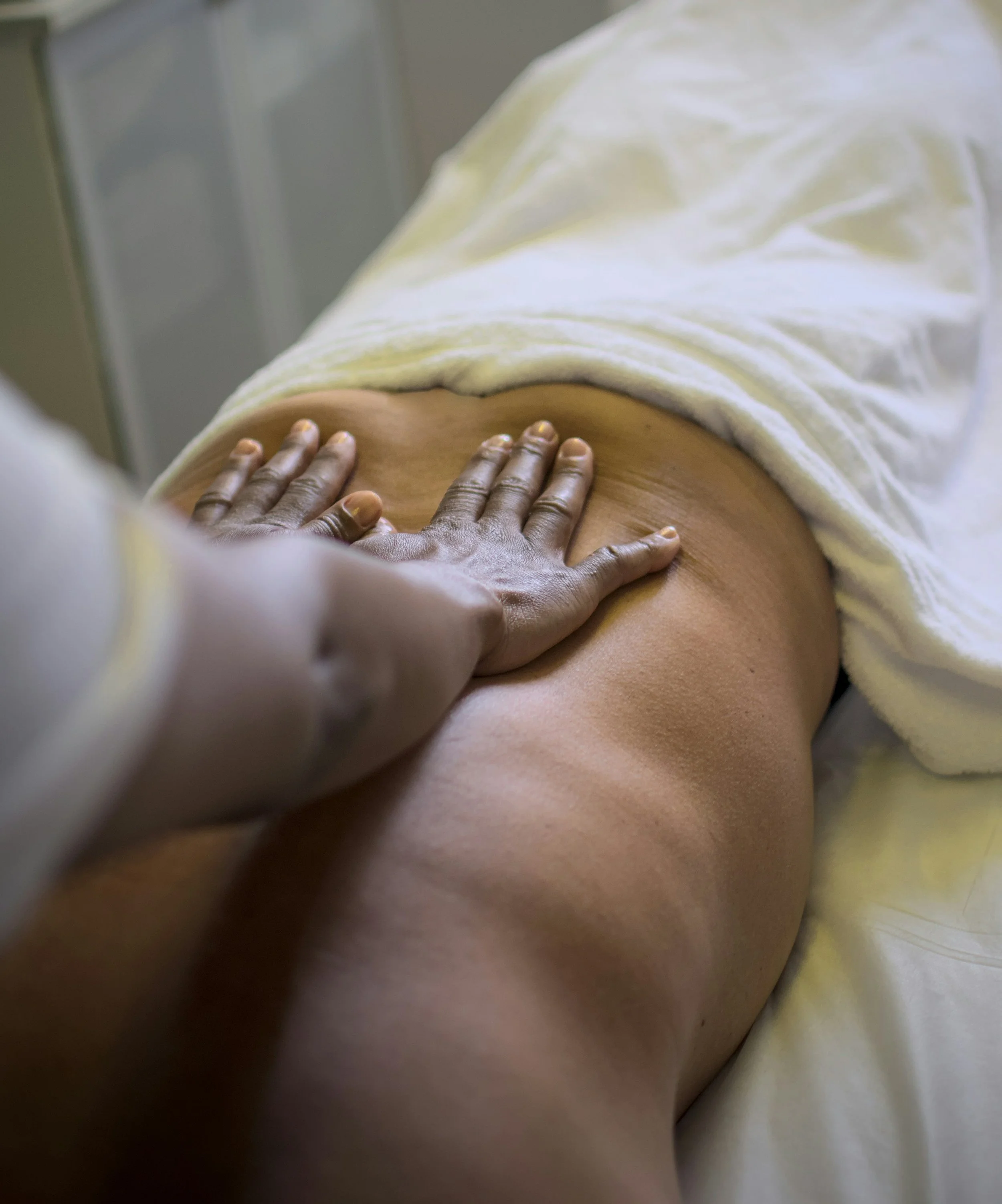 A person receiving a massage on their back with a massage therapist's hand applying pressure.