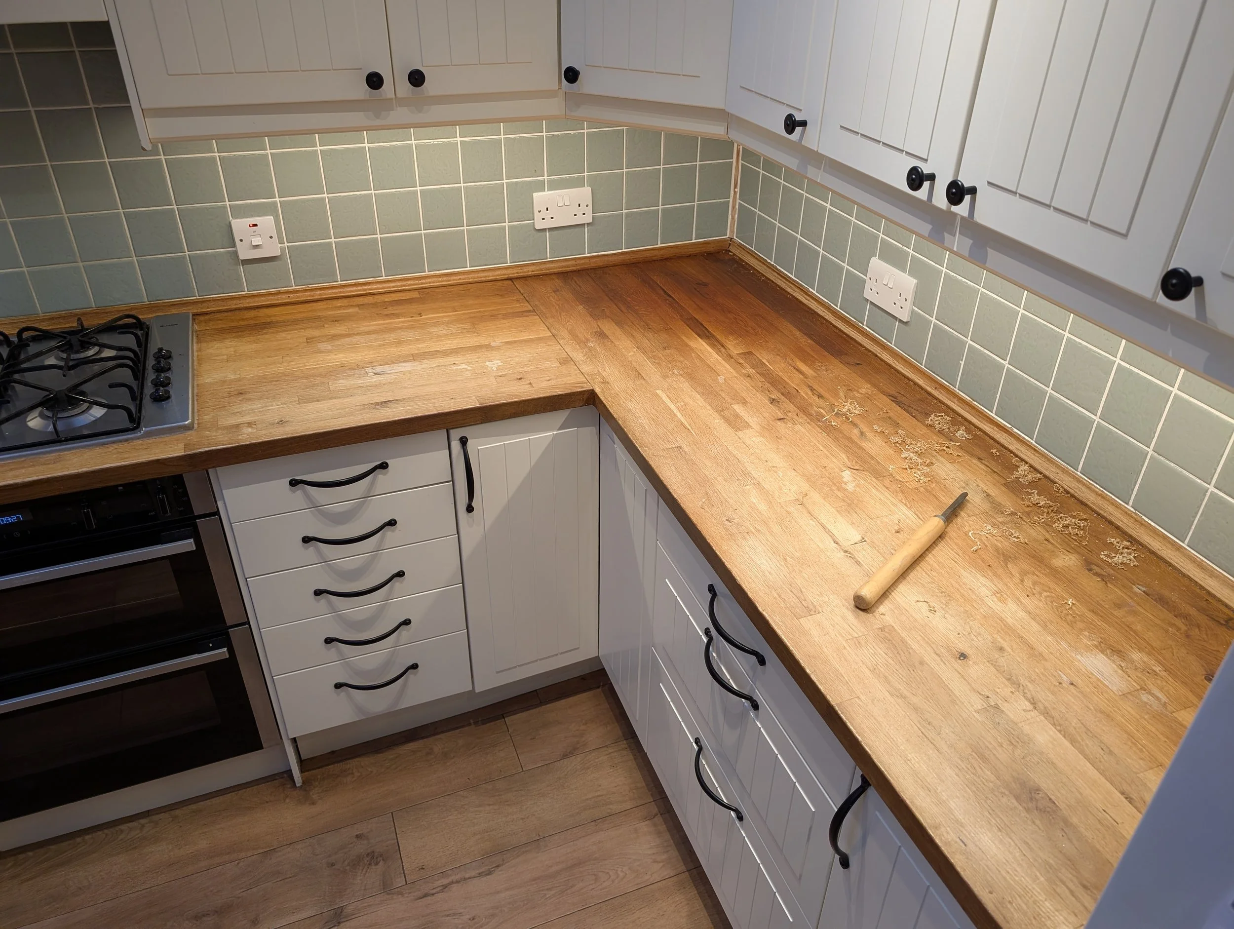 Kitchen countertop with a woodworking chisel, wood grain, and a tiles backsplash.