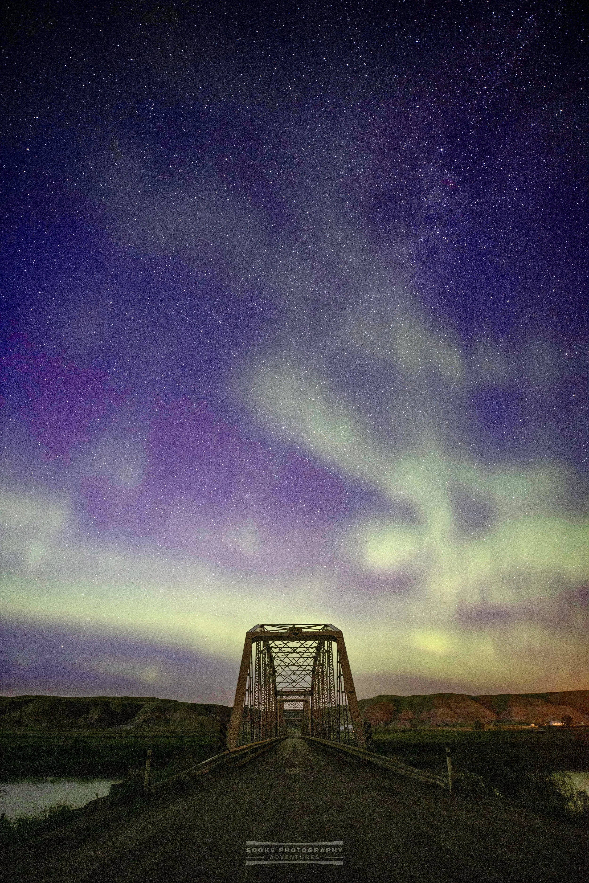 the Northern Lights glow behind a bridge in Alberta