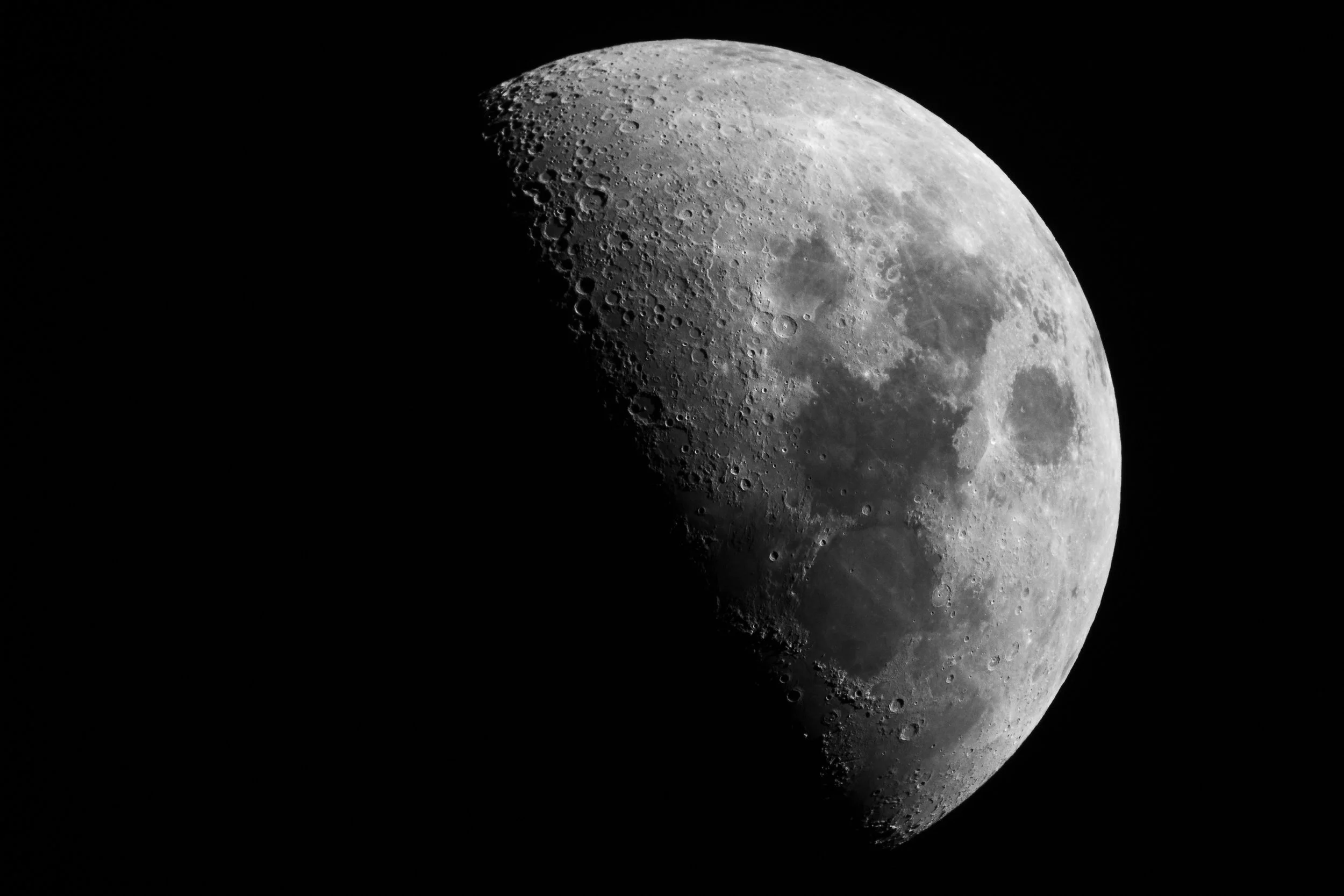 The moon, with the left half in darkness, on a black background