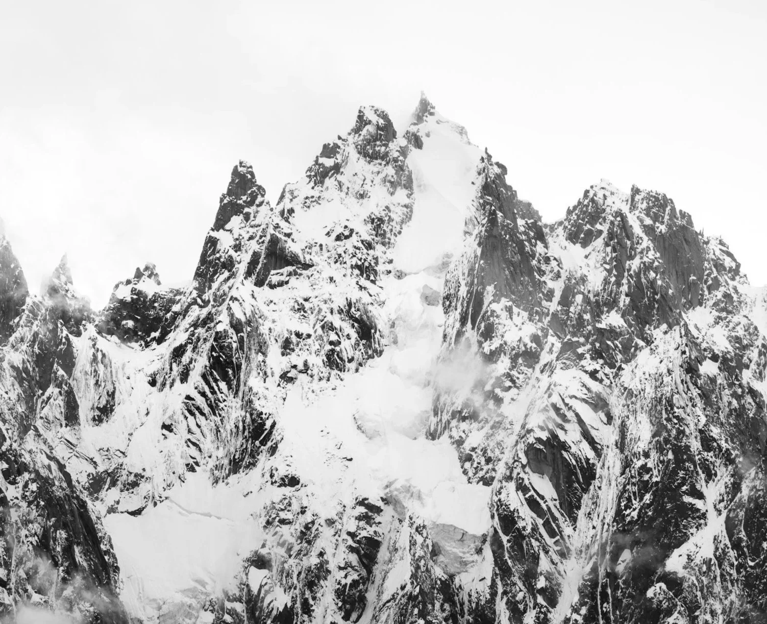 Snow-covered mountain peaks under a cloudy sky.