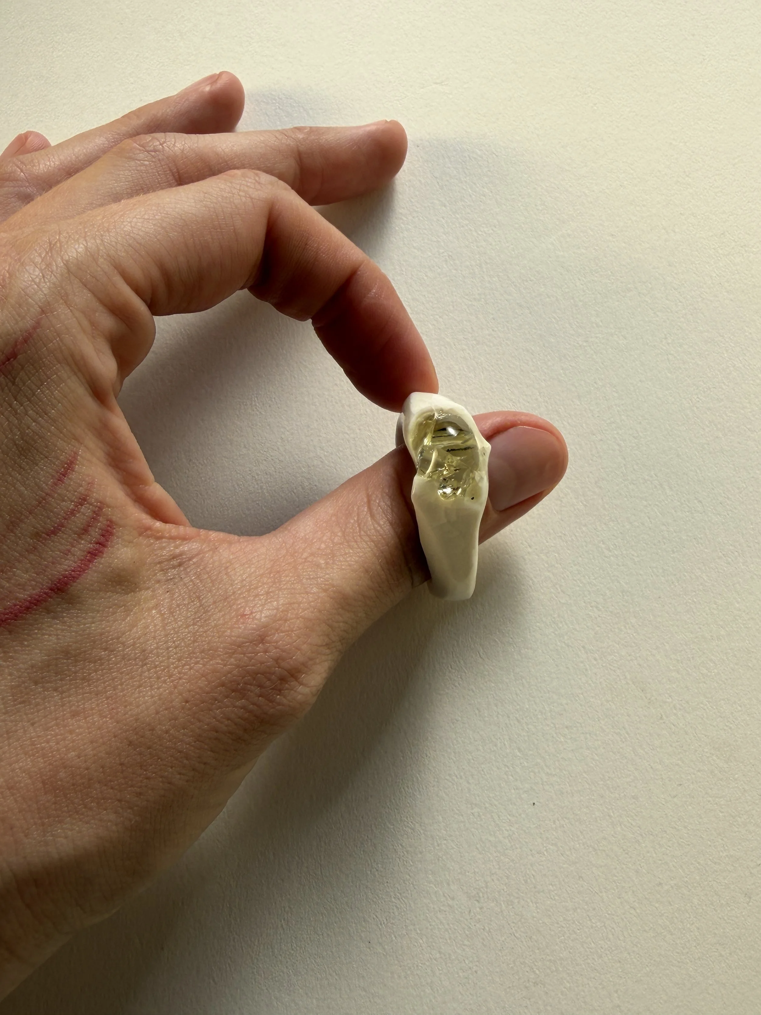 Bone-white porcelain ring with crackle surface worn on hand, soft champagne glass jewel visible
