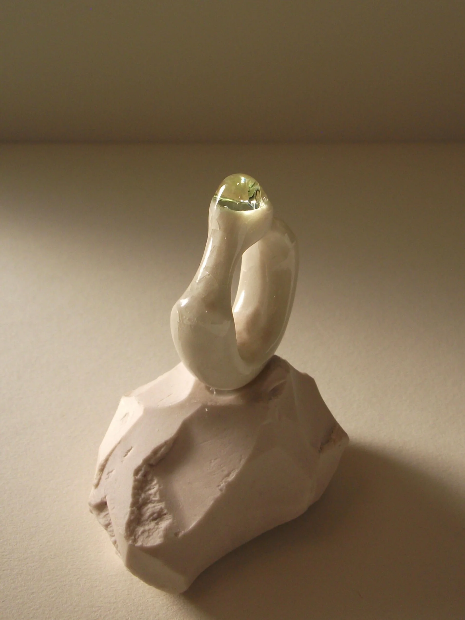 Angled view of bone-white porcelain ring with thick architectural band and glass droplet