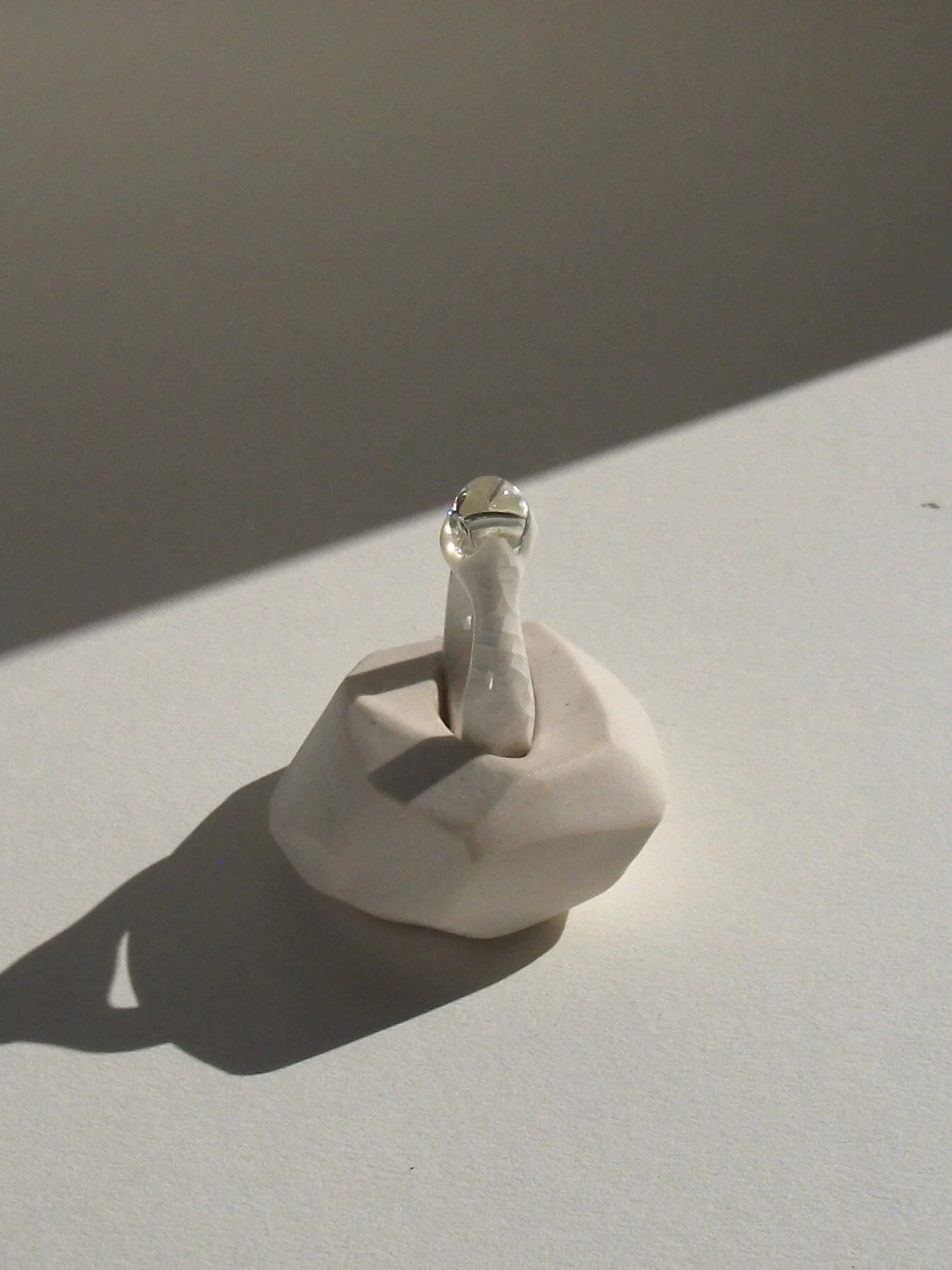 Top view of bone-white porcelain ring with medium-wide band, crackle surface, and large glass droplet