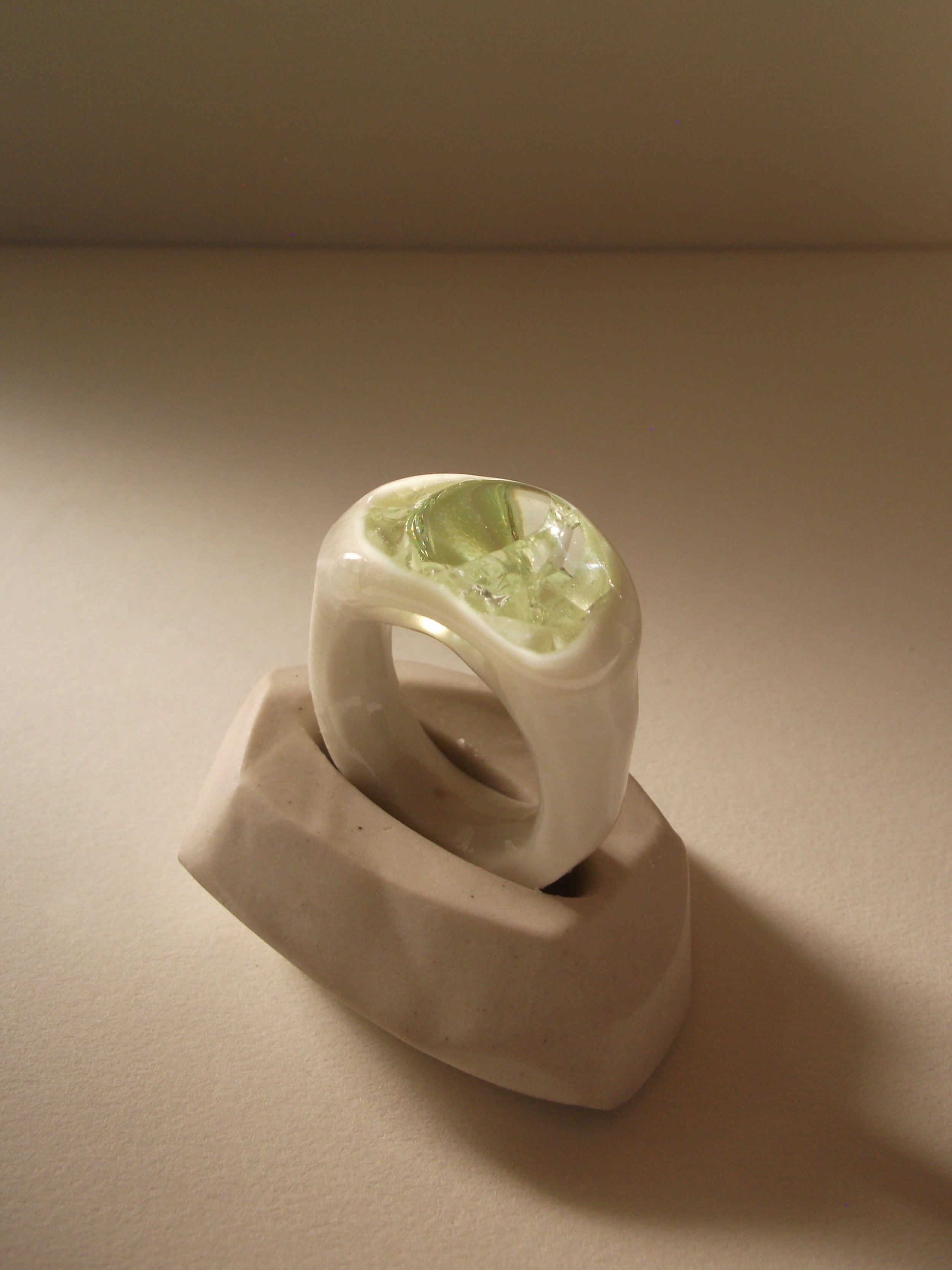 Angled view of bone-white porcelain ring with thick band and glass gemstone