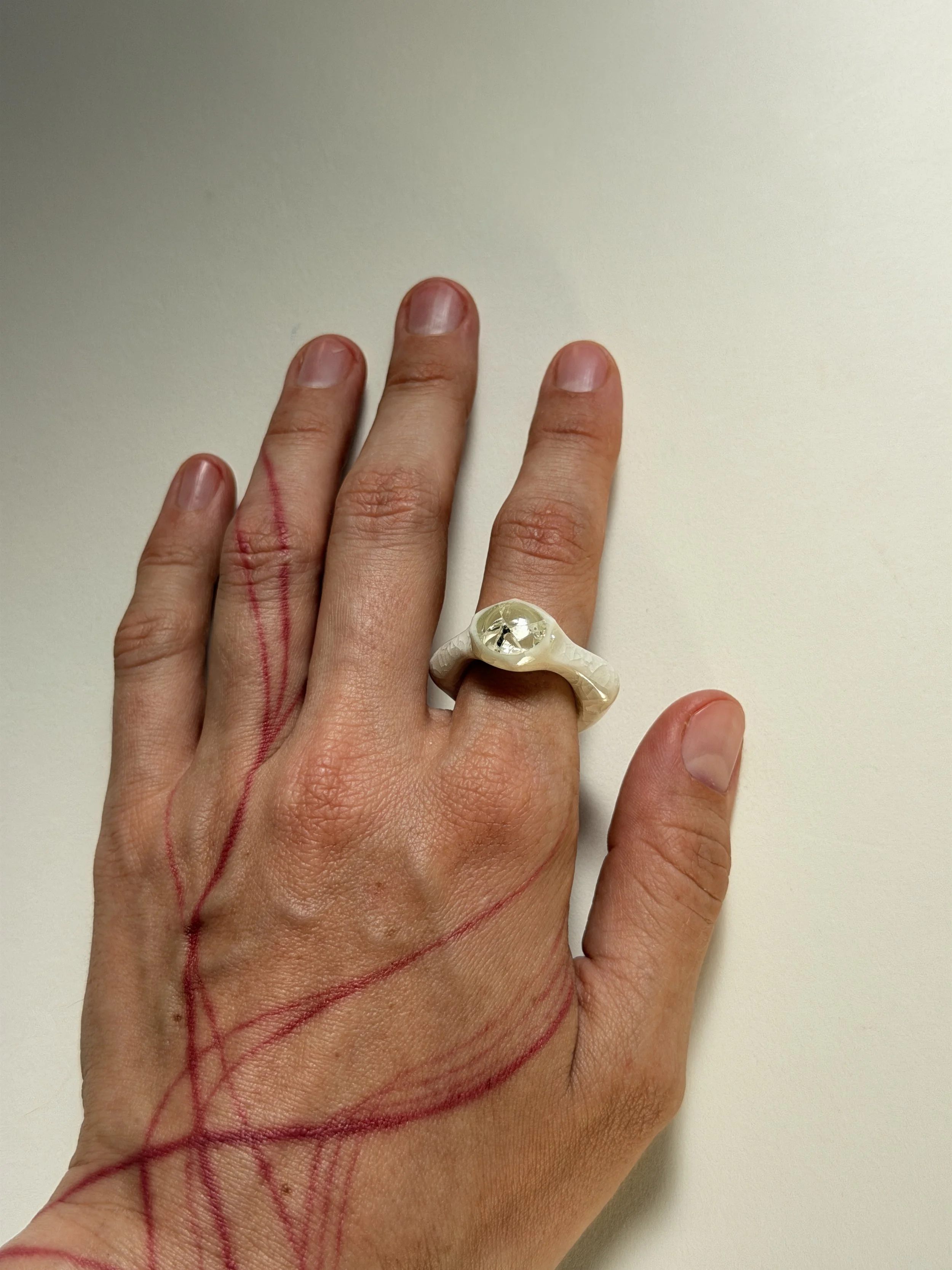 Bone-white porcelain ring with crackle surface worn on hand, glass jewel visible