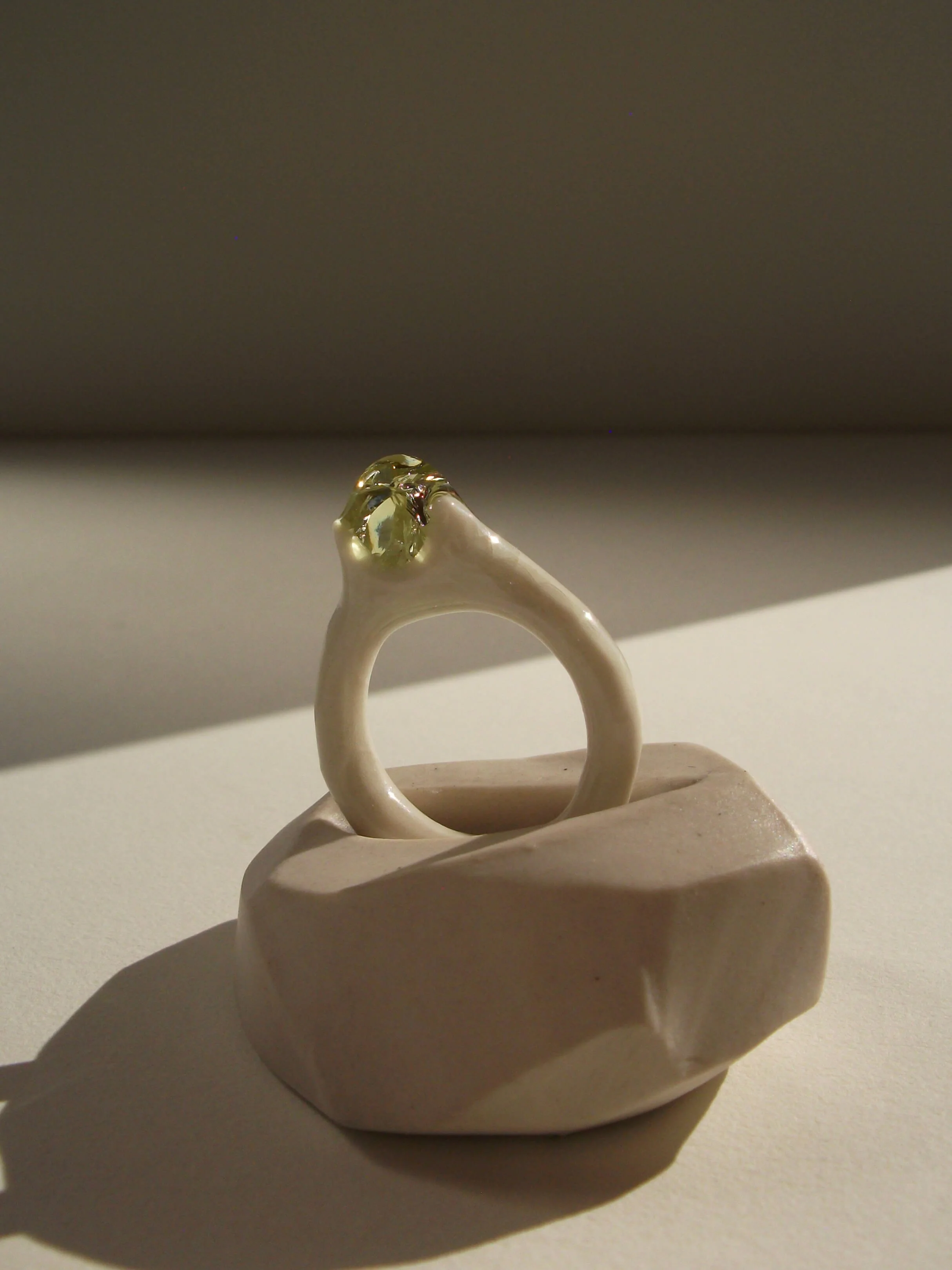 Side view of bone-white porcelain ring with thin band and crackle texture
