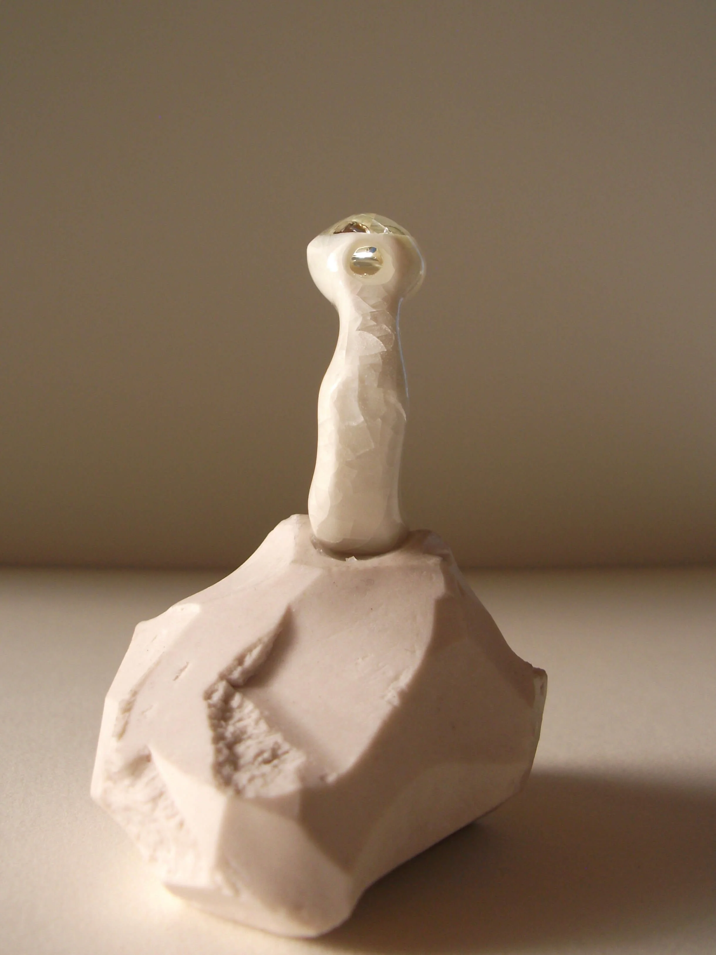 Side view of bone-white porcelain ring with soft crackle surface and glass jewel