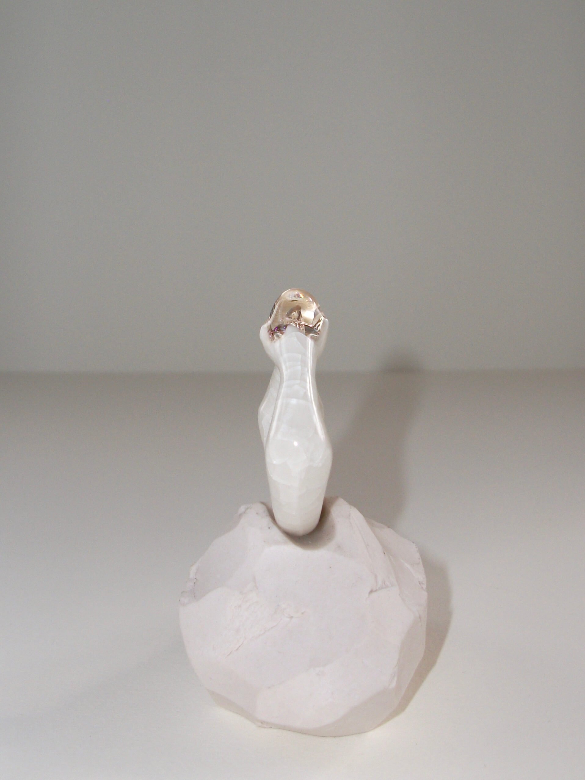 Angled view of bone-white porcelain ring with glass gemstone
