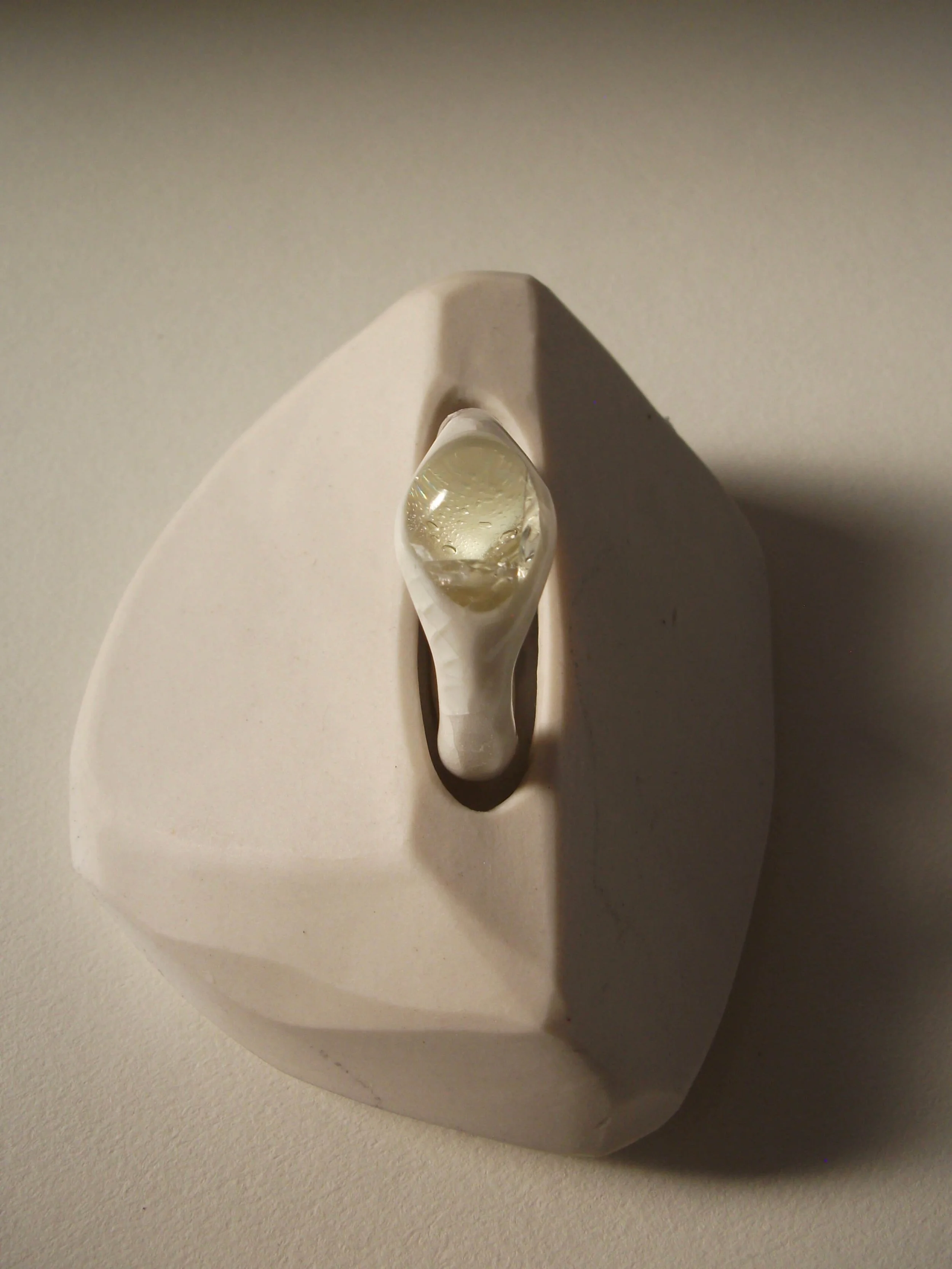Top view of bone-white porcelain ring with crackle surface and central glass jewel