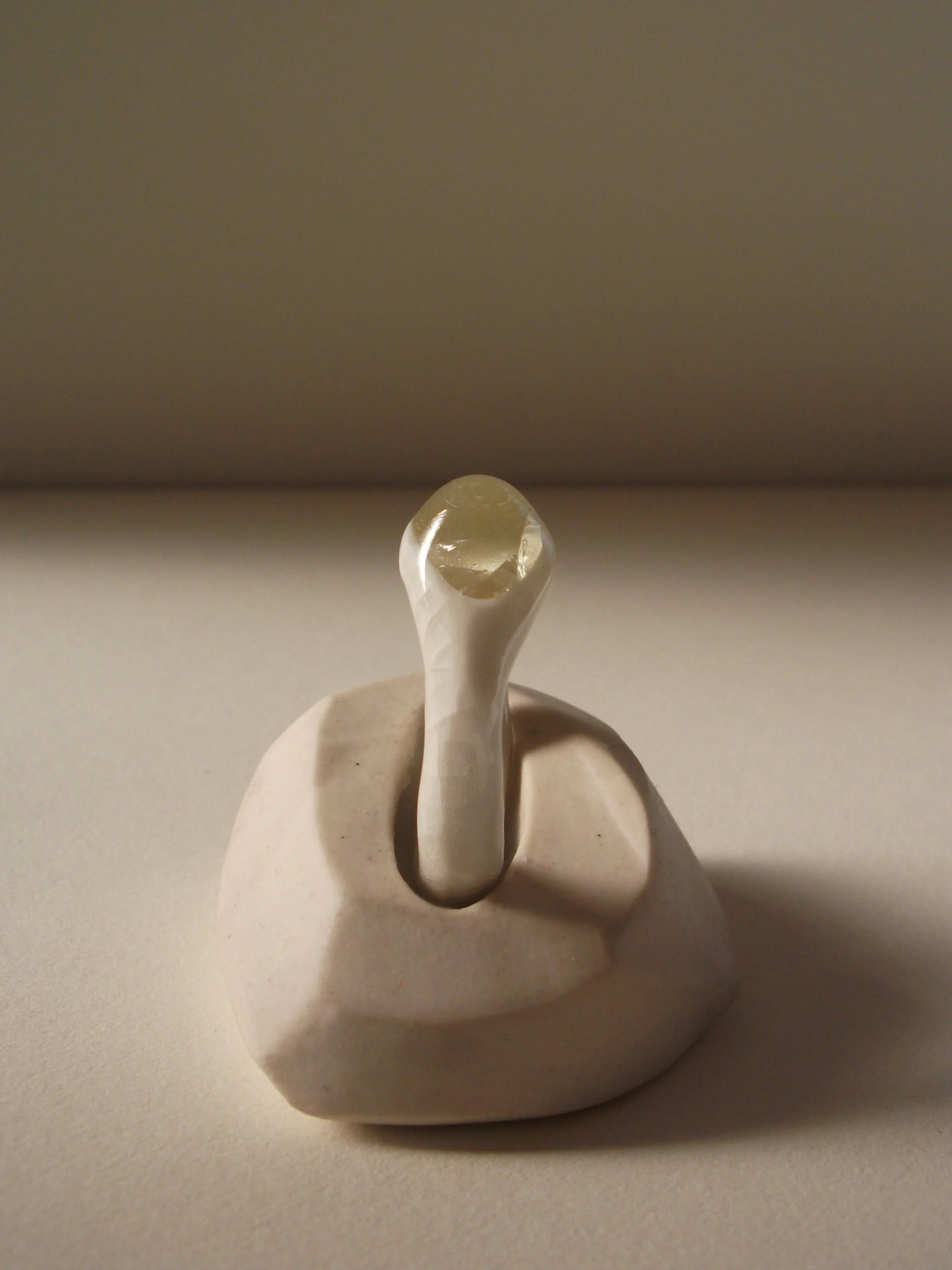 Side view of bone-white porcelain ring with crackle surface and central glass jewel