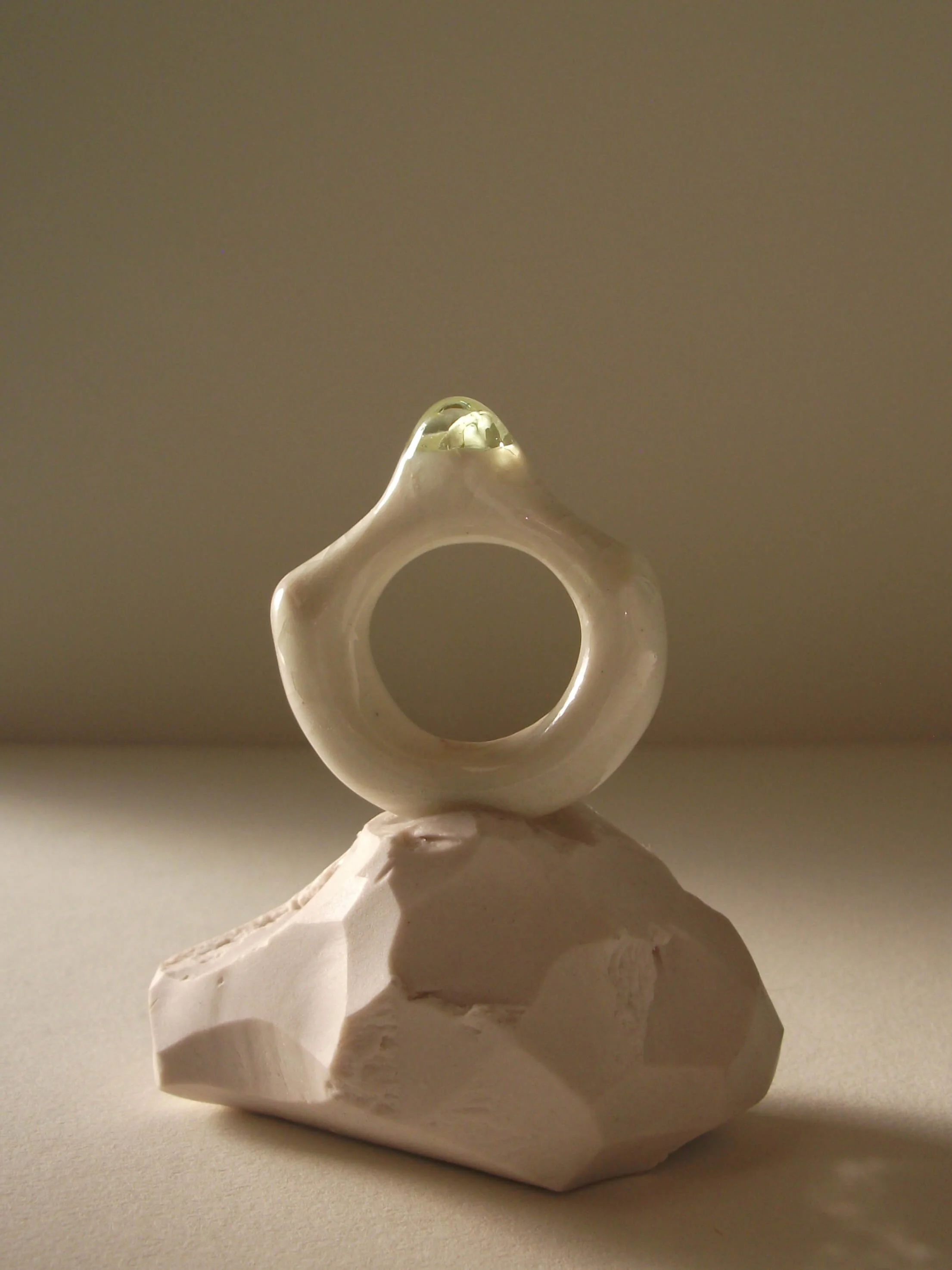Close-up of bone-white porcelain ring with thick architectural band and light celadon glass droplet