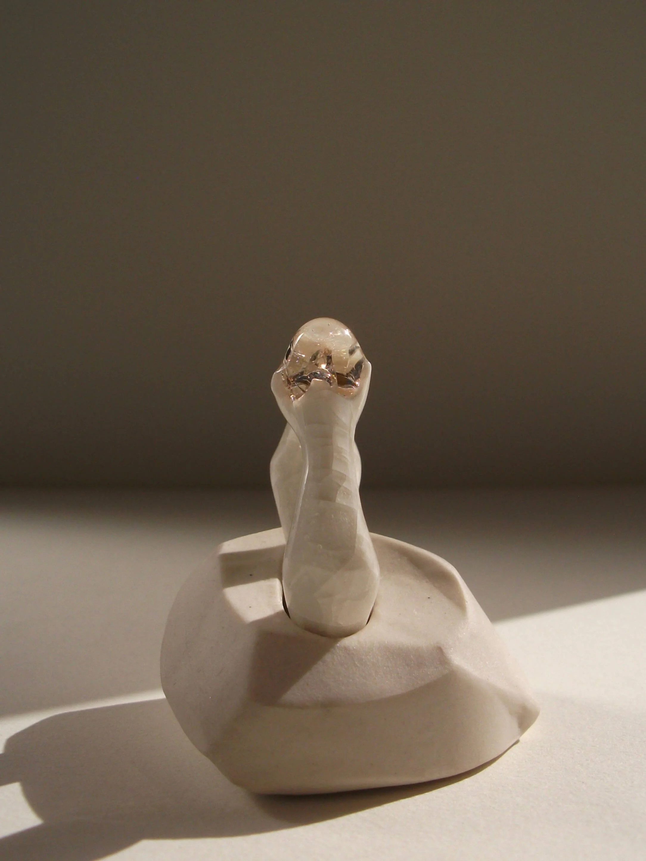 Angled view of bone-white porcelain ring with glass gemstone