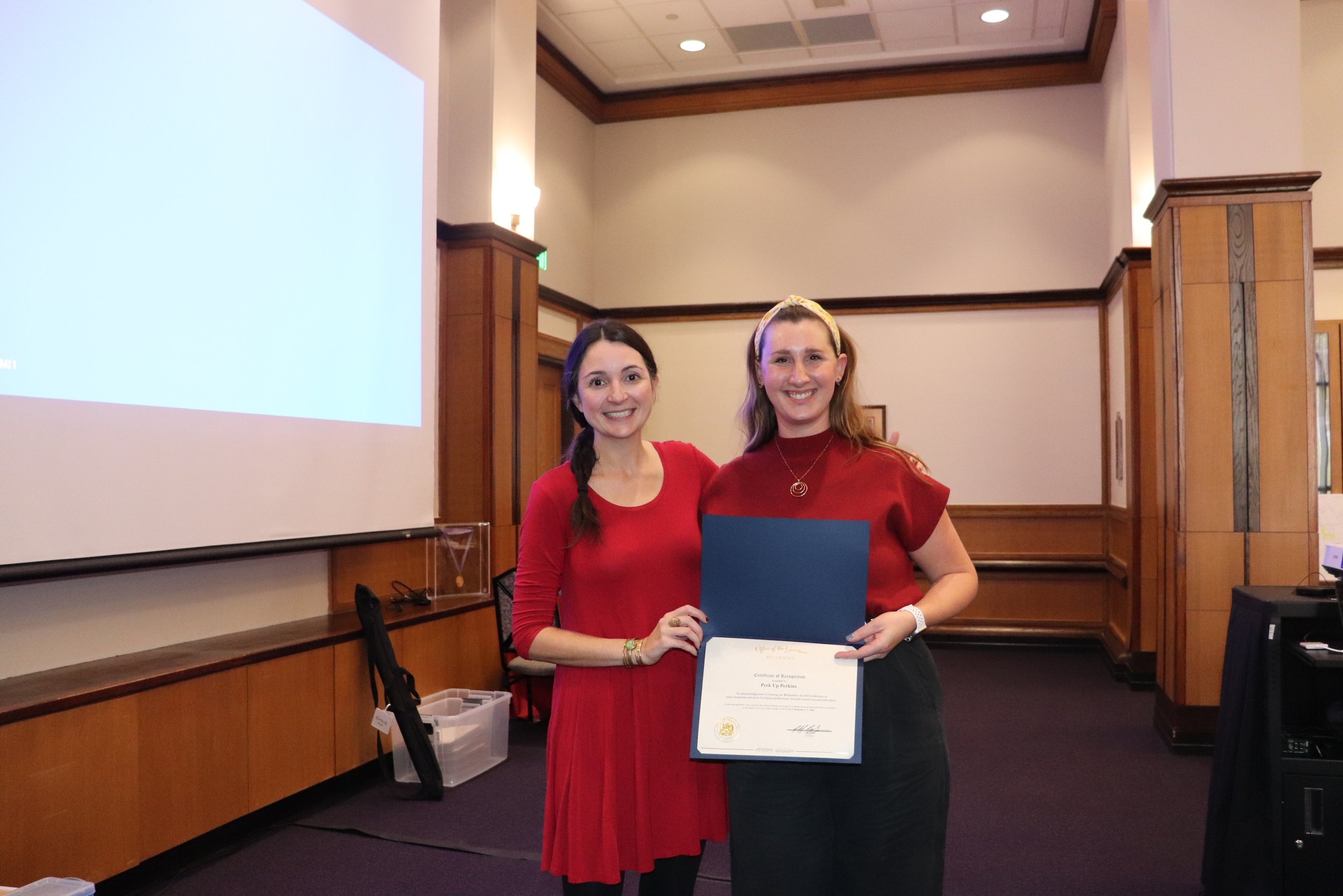 Two women hold a proclamation from the governor.