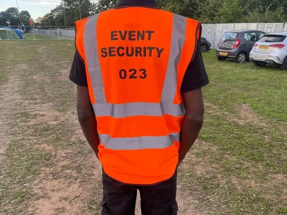 A mountain landscape with snow-capped peaks in the background and rolling green hills with a modern building in the foreground.