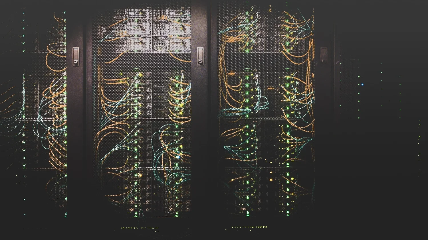 Server racks with illuminated network cables in a data center.