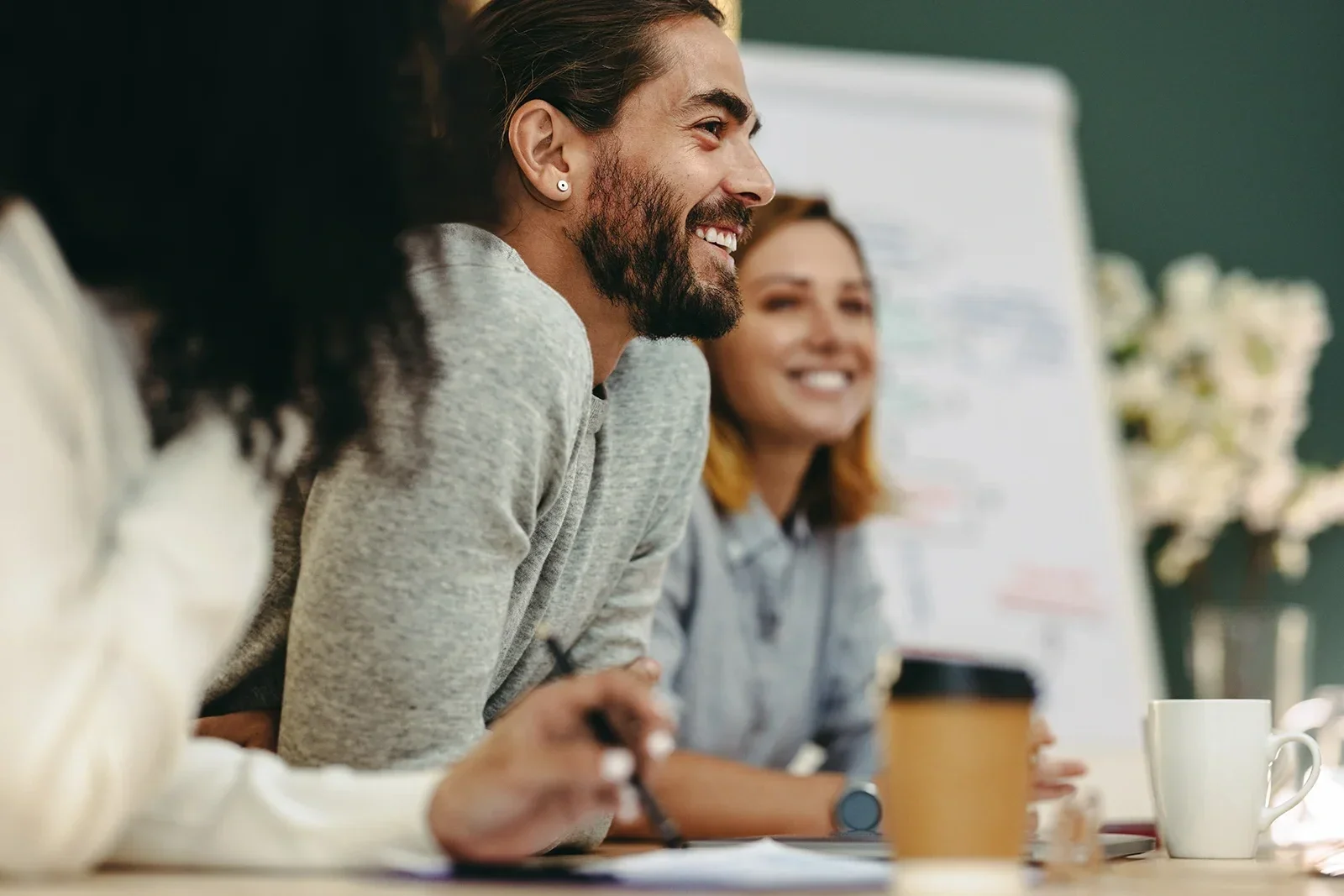Group of Arts professionals sitting at a table during a meeting, smiling and engaged in conversation, satisfied with their execution.