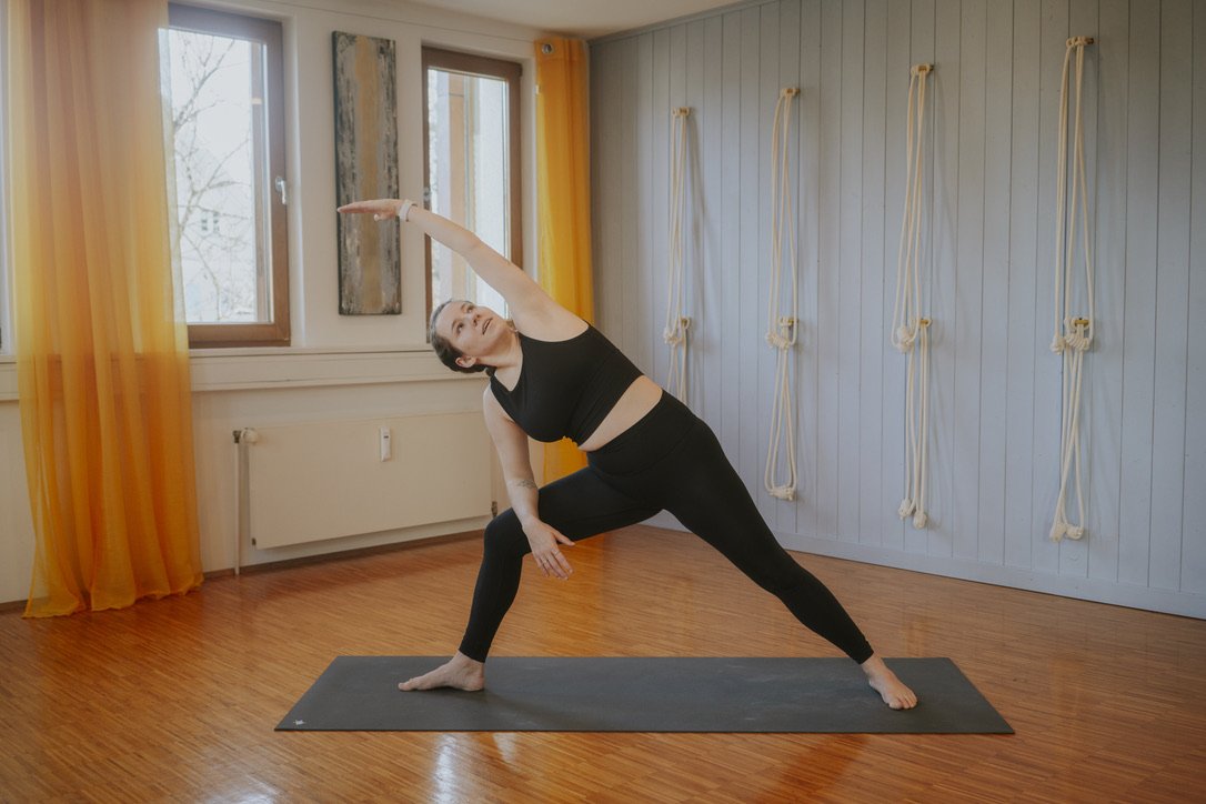 Sophia auf Yogamatte macht das seitlich gestreckte Dreieck (Yogahaltung)
