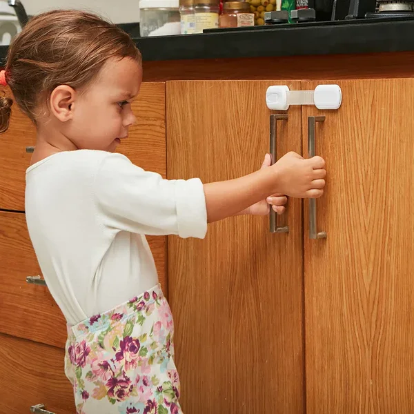 A young girl opening a kitchen cabinet door with her arm stretched out.