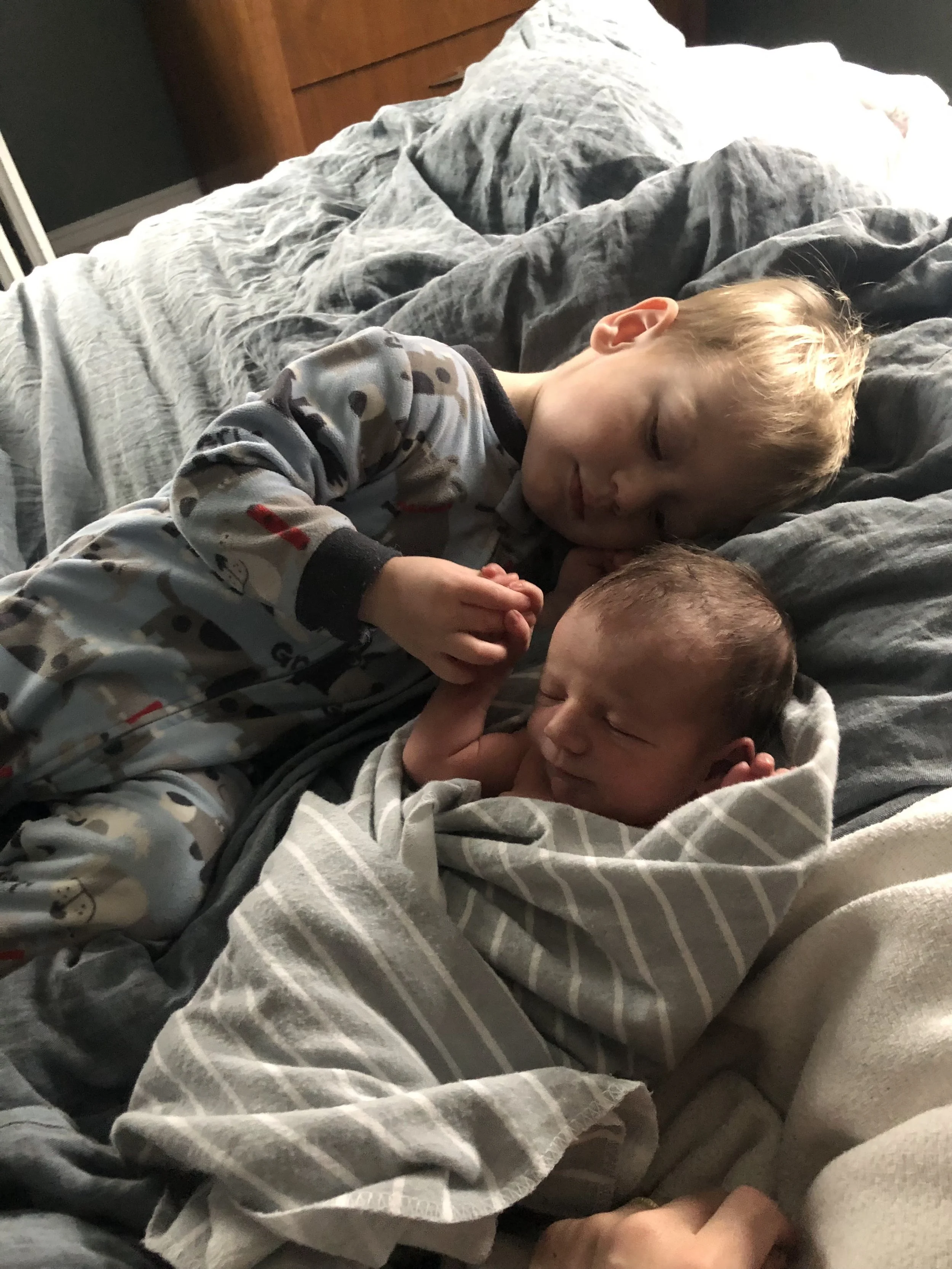 young boy holding his newborn brother's hand