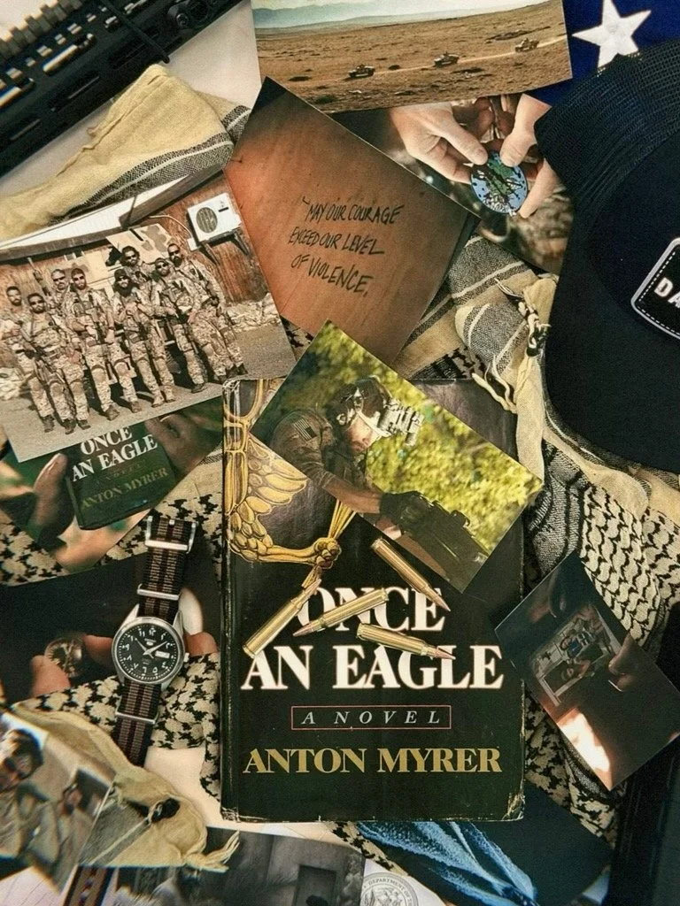 A collection of military-related items including the book "Once an Eagle" by Anton Myrer, a watch with a NATO strap, several photographs of soldiers, military vehicles in a desert, a patch with the word "DAYS" on it, and a printed quote about courage