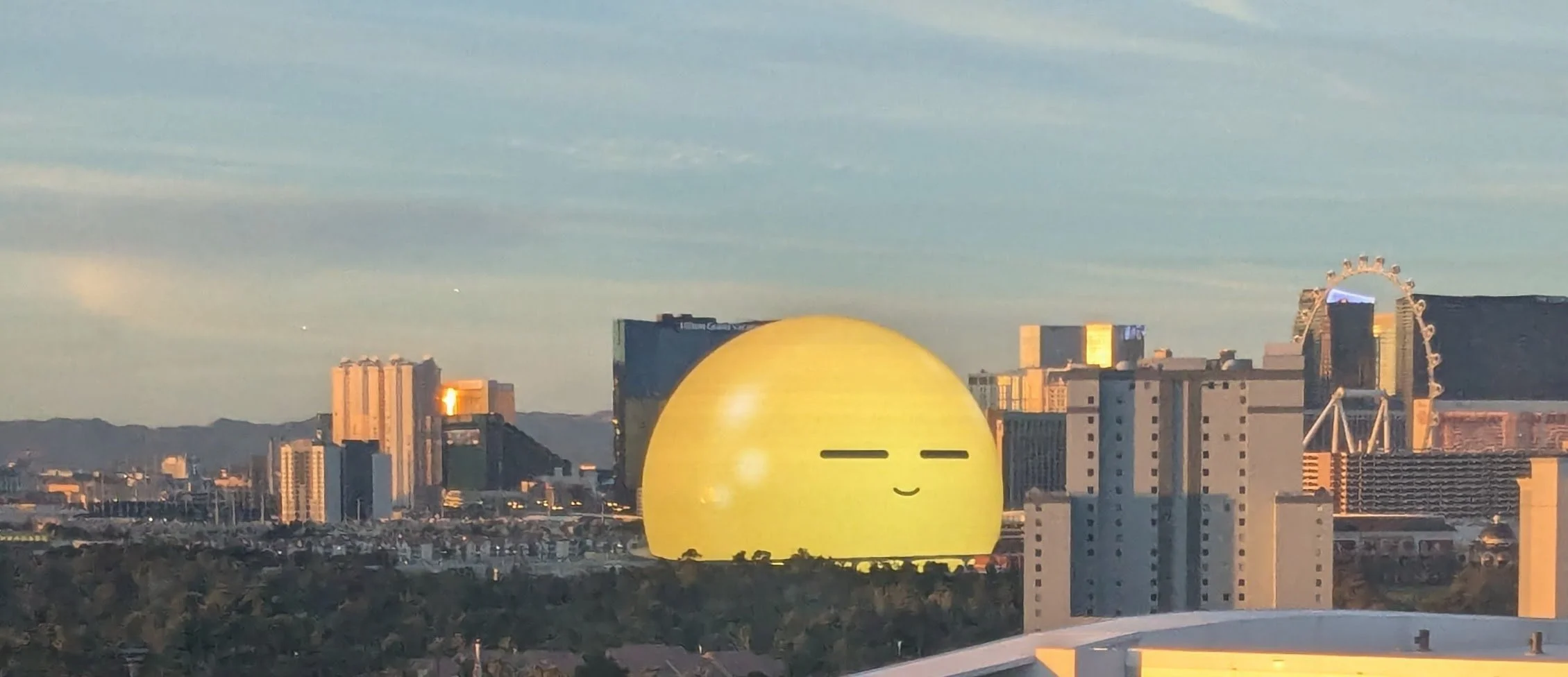 A large spherical building with a smiley face, set in an urban skyline with a Ferris wheel.