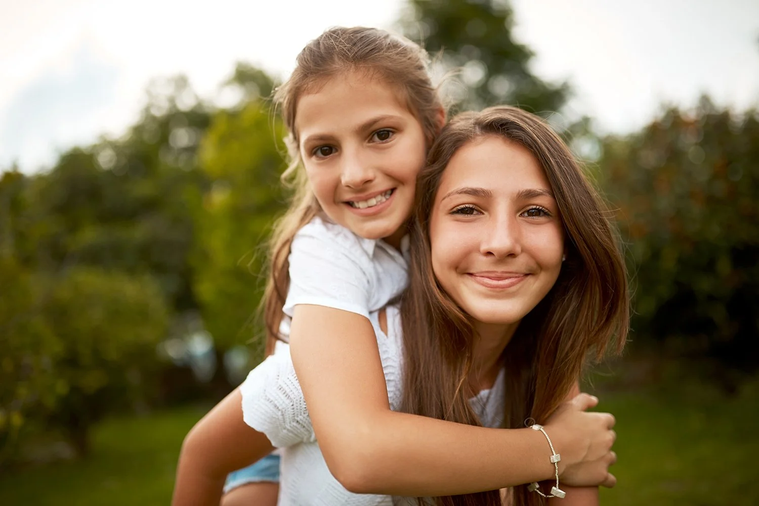 Piggyback ride, two happy girls at the park, having fun.