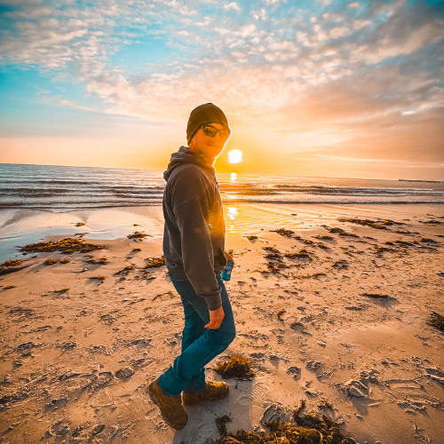 Che is walking along a sandy beach during sunset, at Port Hughes, South Australia
