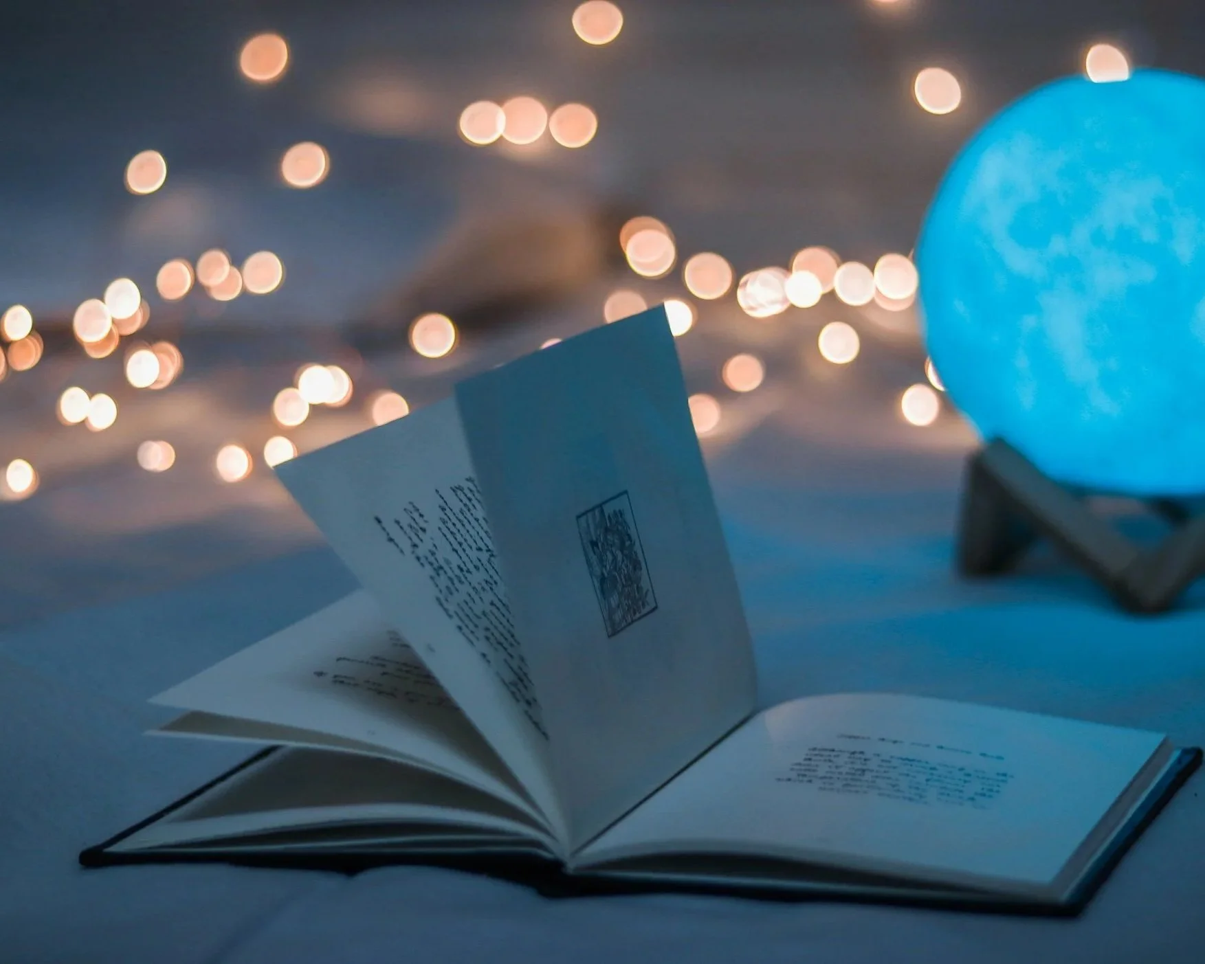 Open book with twinkle lights in background and blue crystal ball providing ambiance.