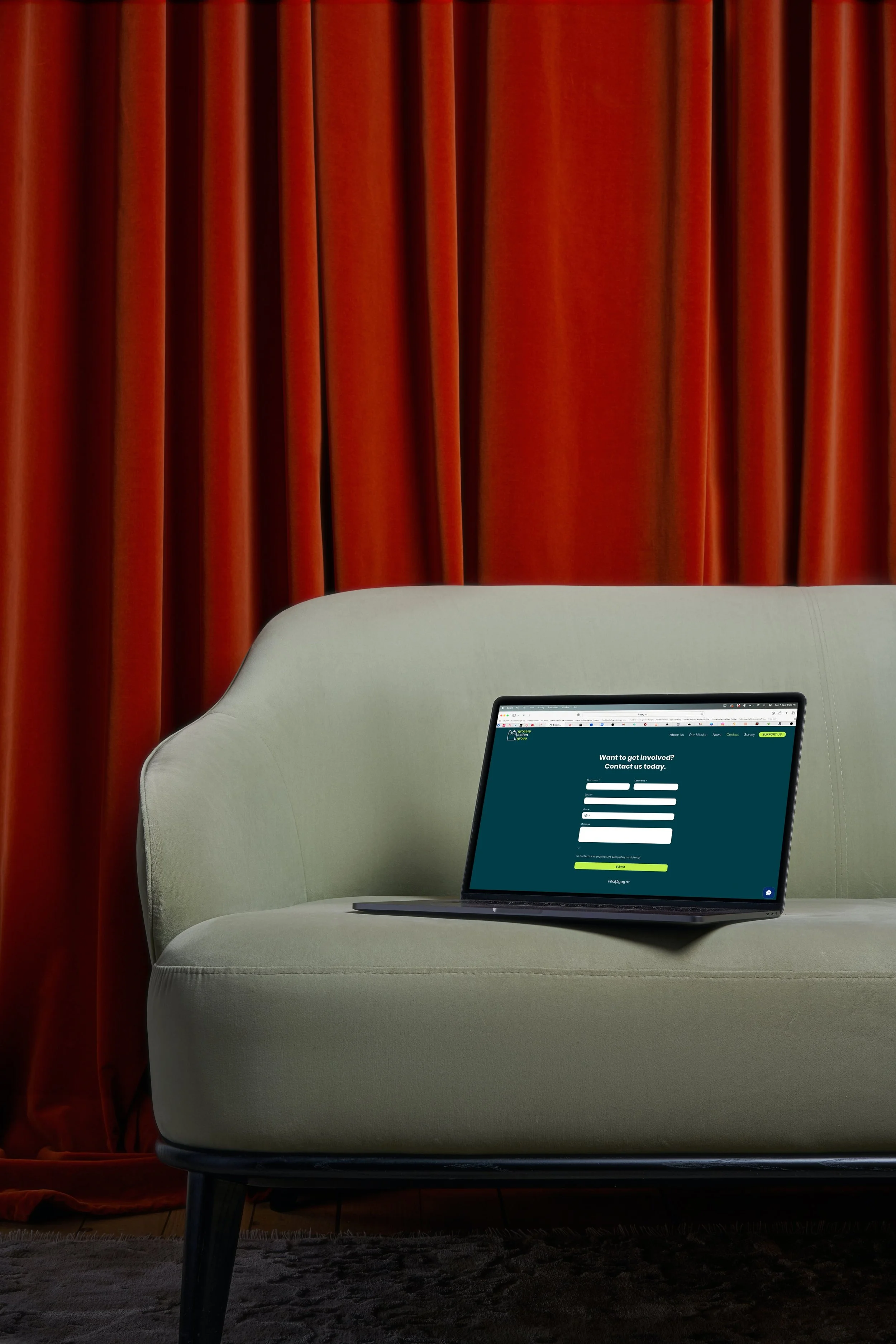 Laptop sitting on couch displaying contact info for Grocery Action Group