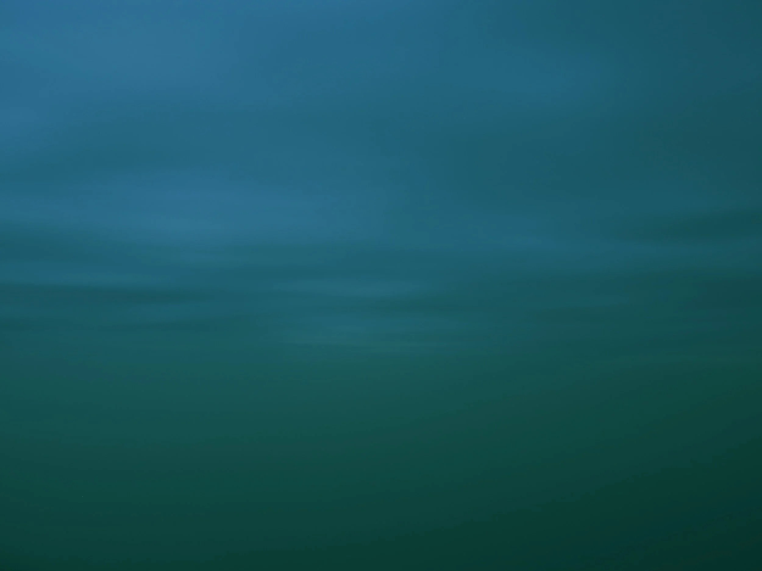 A blurred landscape of a body of water with a sky above, with no distinct objects visible.