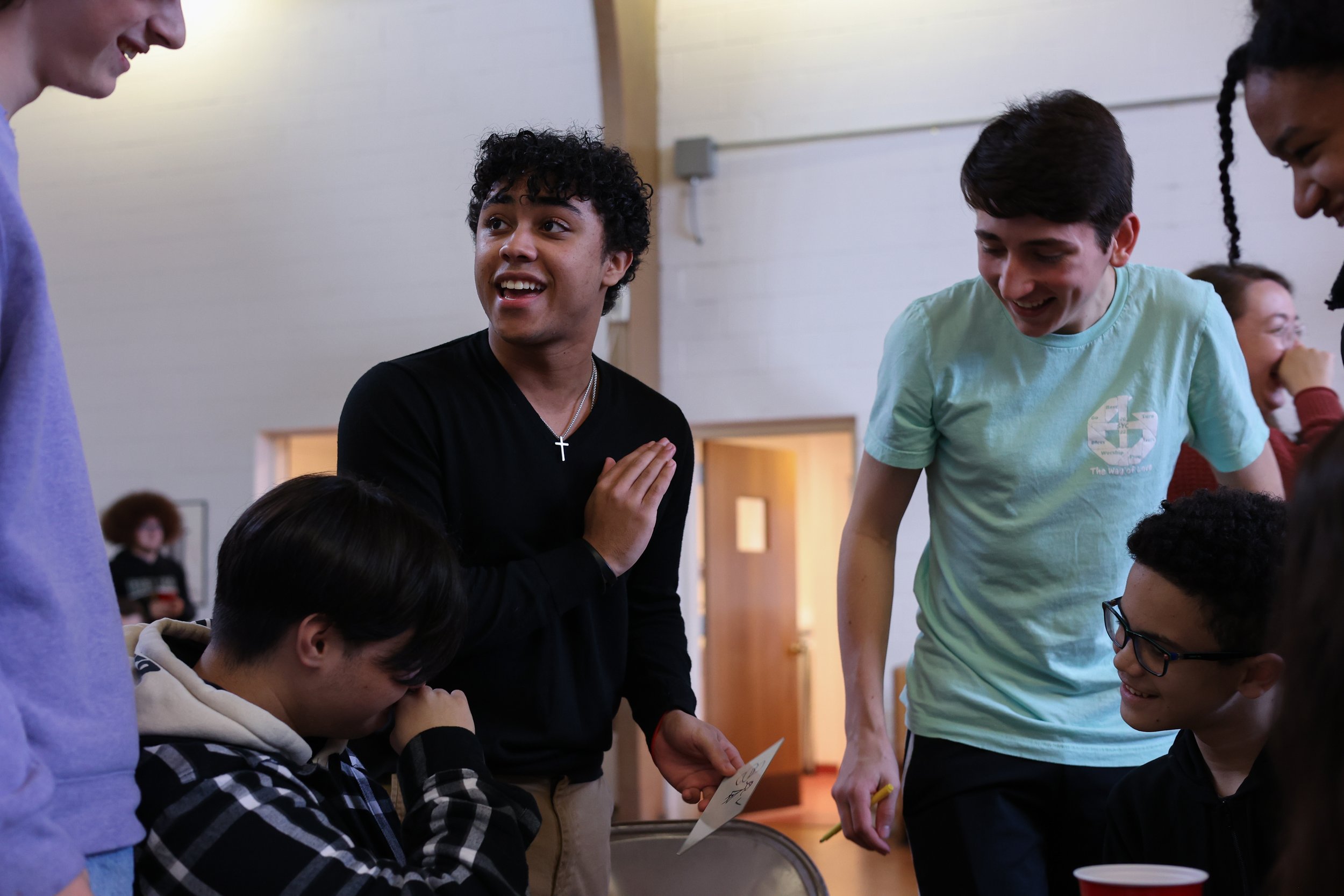 Group of diverse young people smiling and talking in a casual indoor setting.