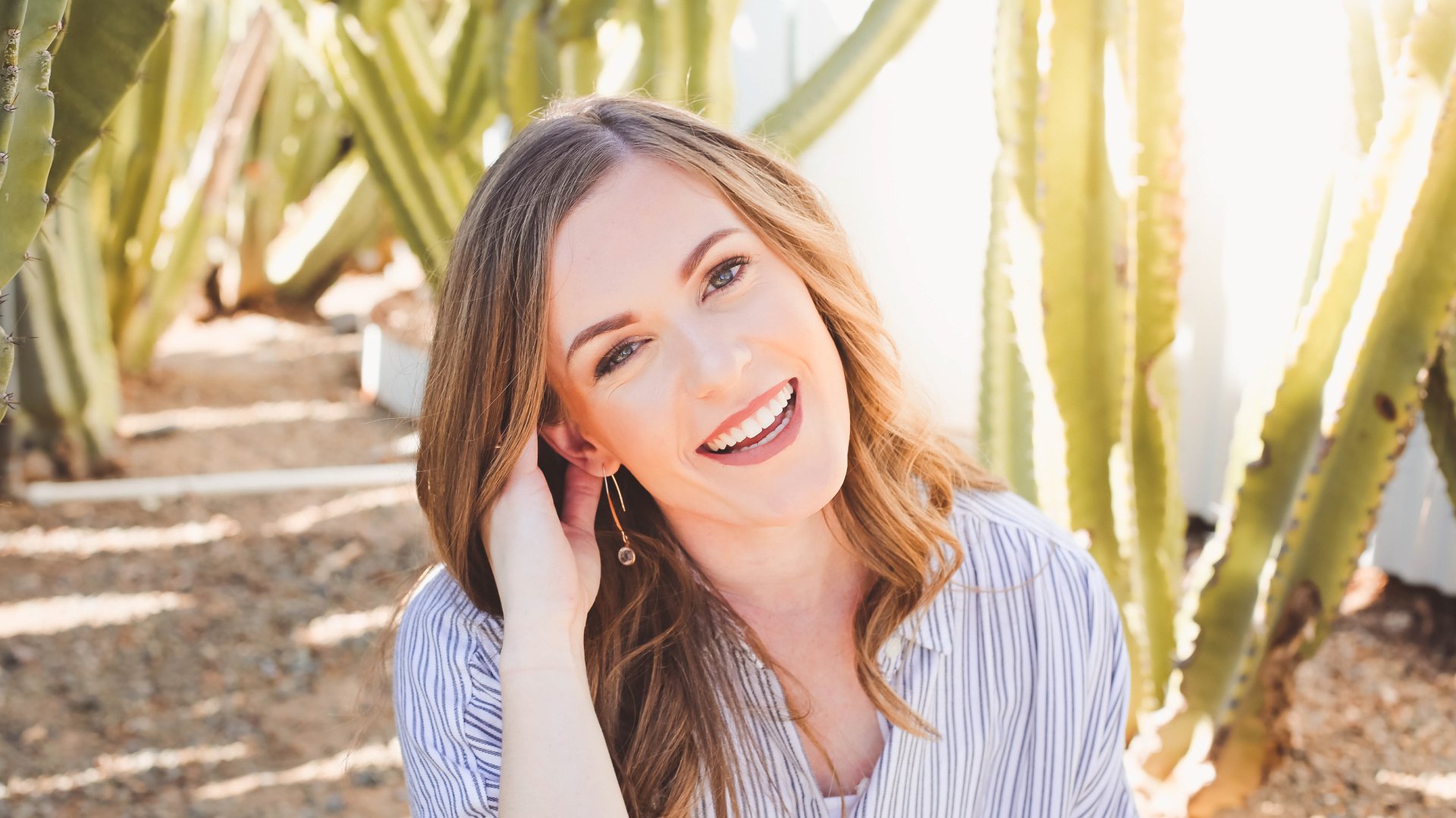 Carly Gieszl smiles at the camera while sitting outside surrounded by cacti