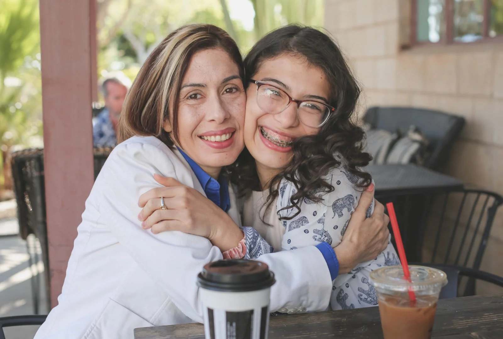 A parent and their student hug one another as they smile at the camera