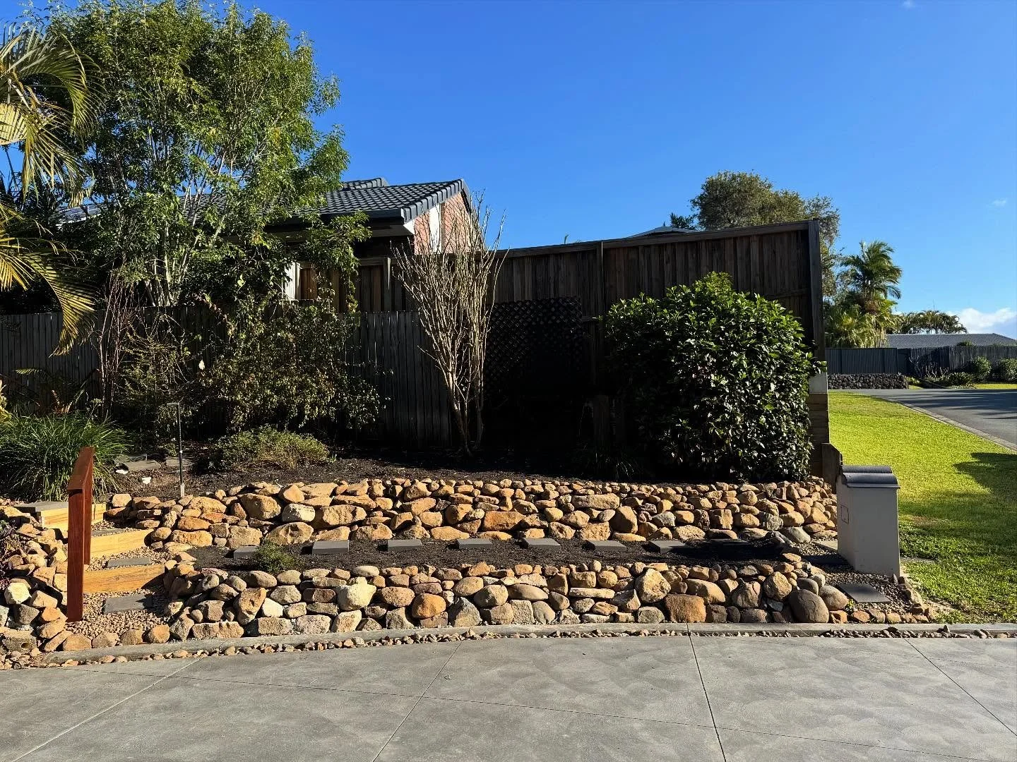 Robina project completed!
We constructed a two tier bush rock retaining wall, prepared new garden beds, filled with an organic soil mix, primed for planting. 
A custom Merbau handrail was also constructed along with treated pine sleeper steps aiming 