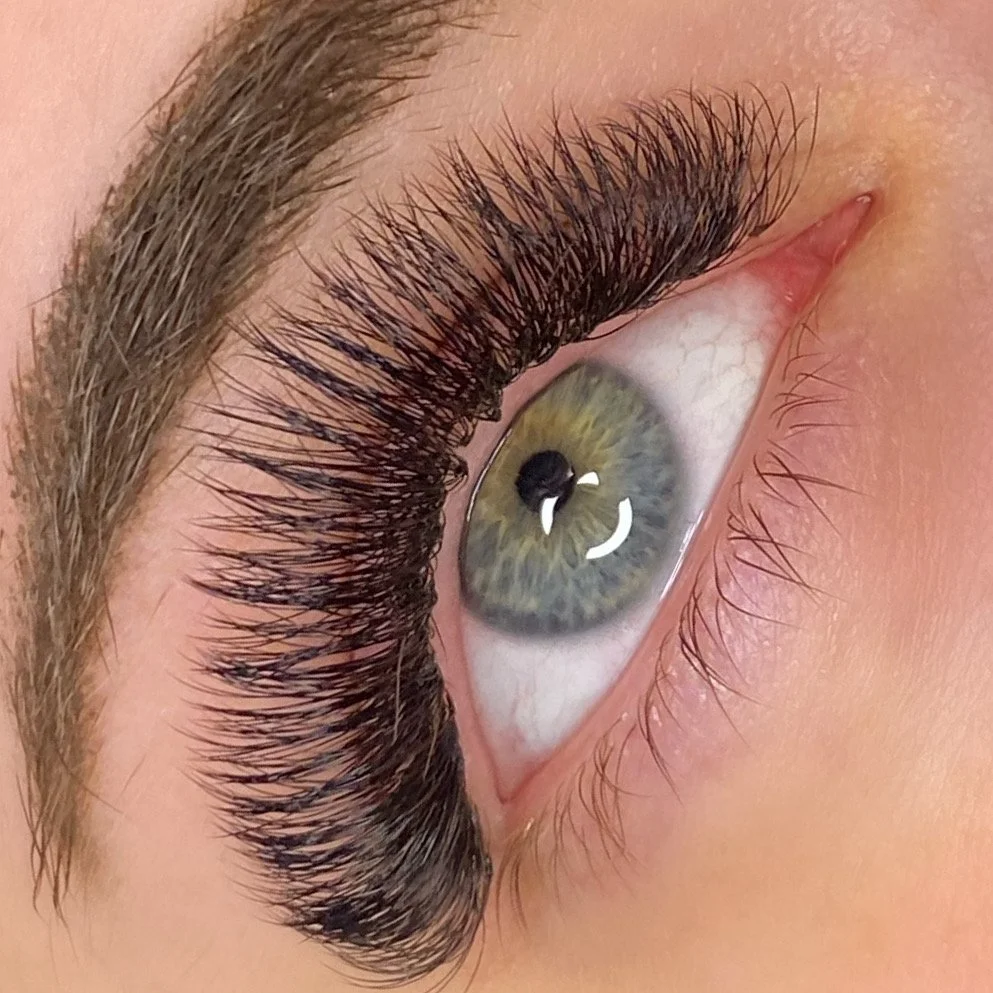 Close-up of a green eye with long, thick eyelashes.