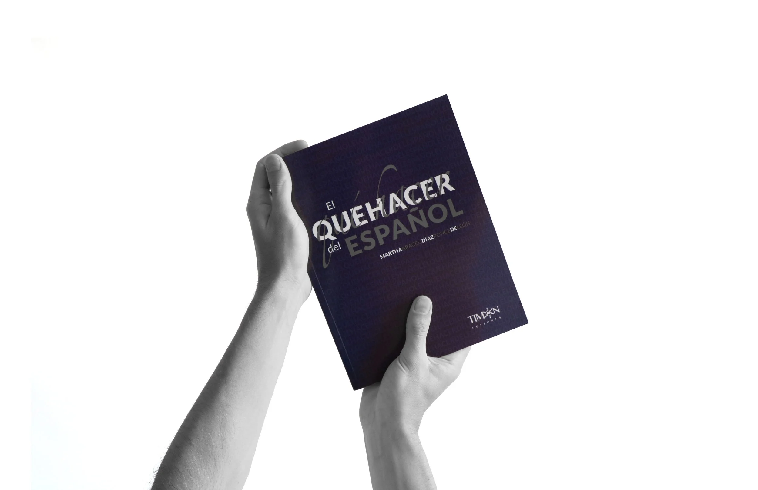Black and white photo of hands holding a book titled 'El Quehacer del Español' by Martha Araceli Díaz Ponce, with a white background.